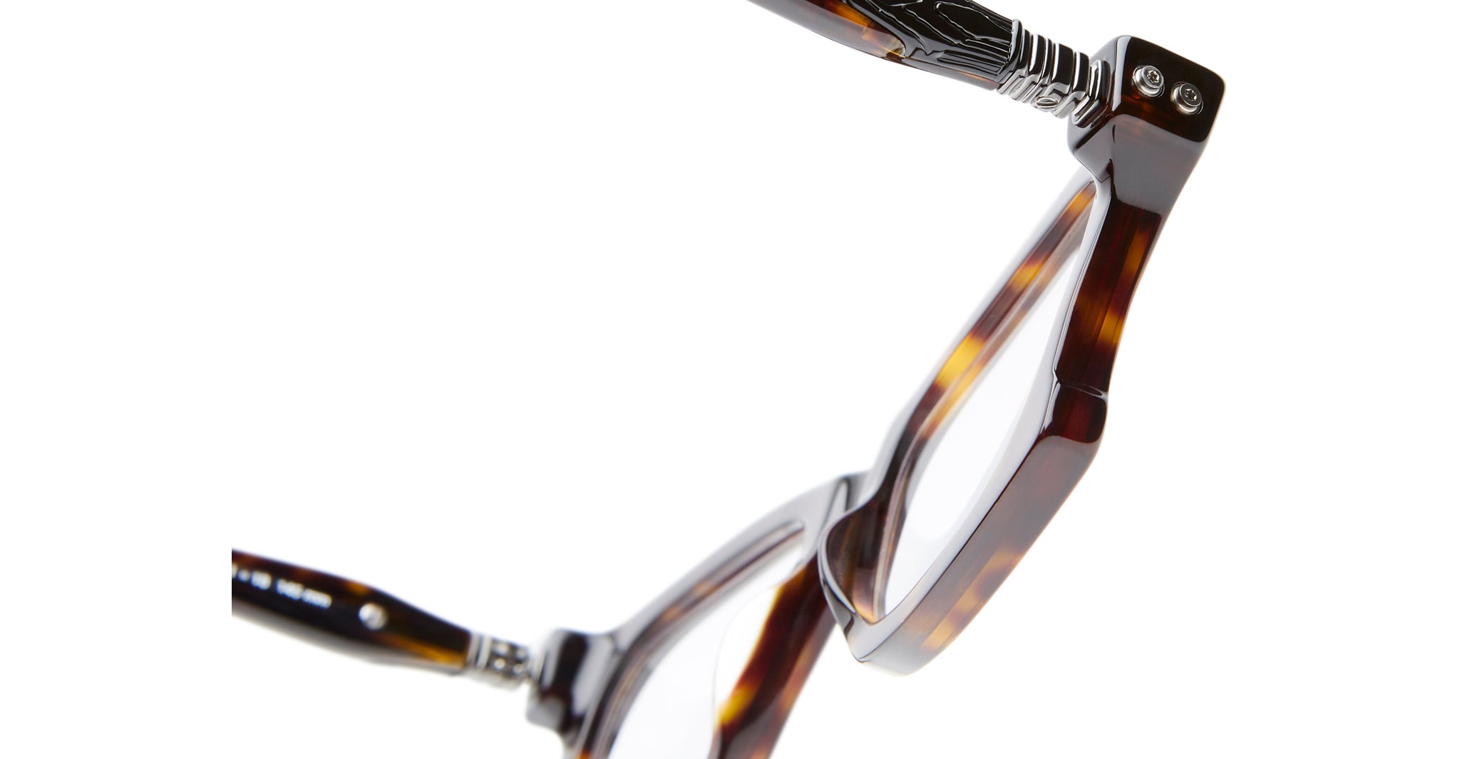 Close-up of Kuboraum D75 brown tortoiseshell eyeglasses with metal hinge detail, set against a white background. The image highlights the frame’s texture and precise construction.