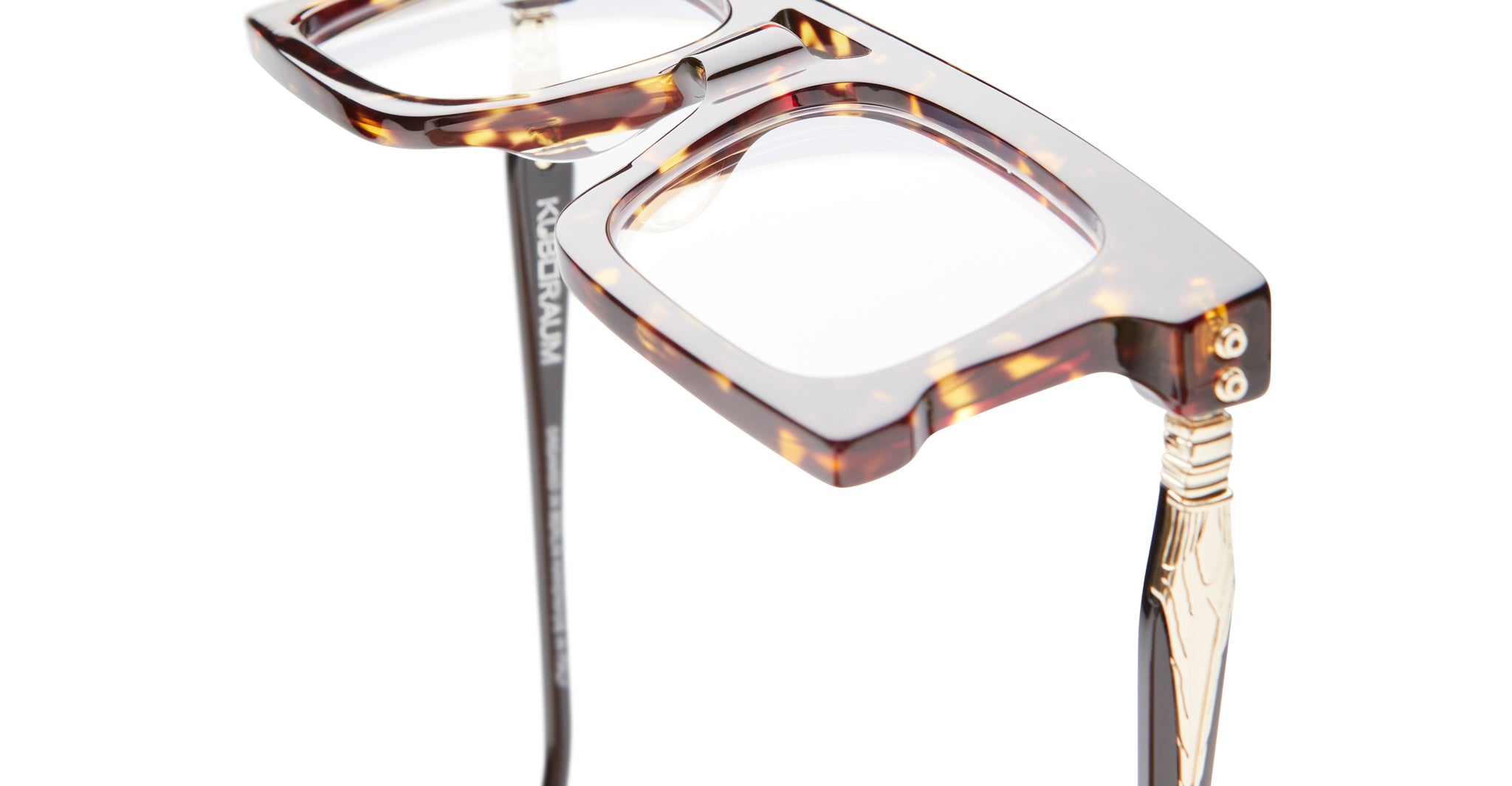 Close-up of Kuboraum D76 eyeglasses by KUBORAUM, rectangular tortoiseshell frames with gold-detailed temples, front view.