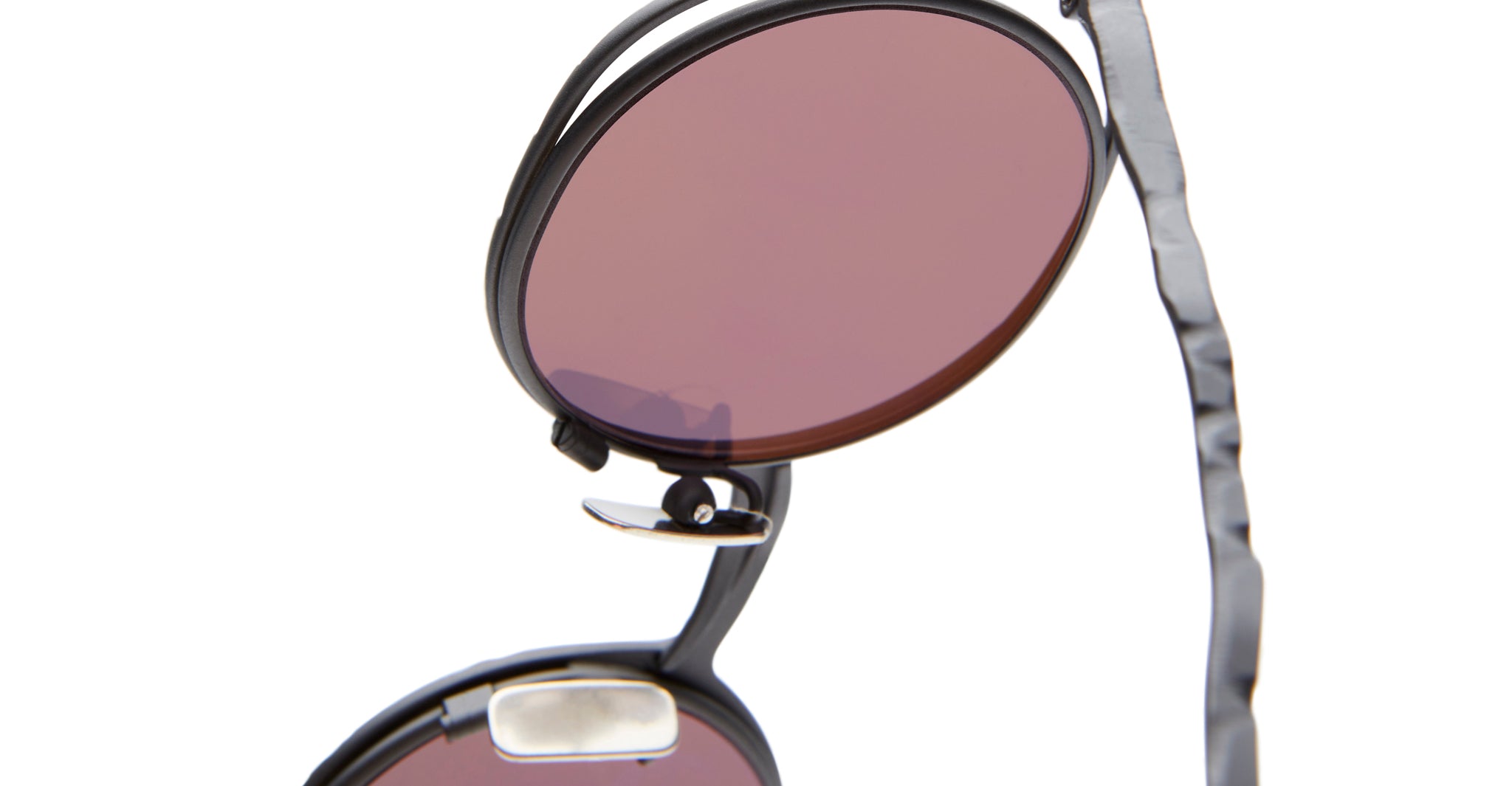 Close-up of Kuboraum H11 black-framed sunglasses featuring round, tinted pink lenses and a metal nose pad, displayed against a white background.