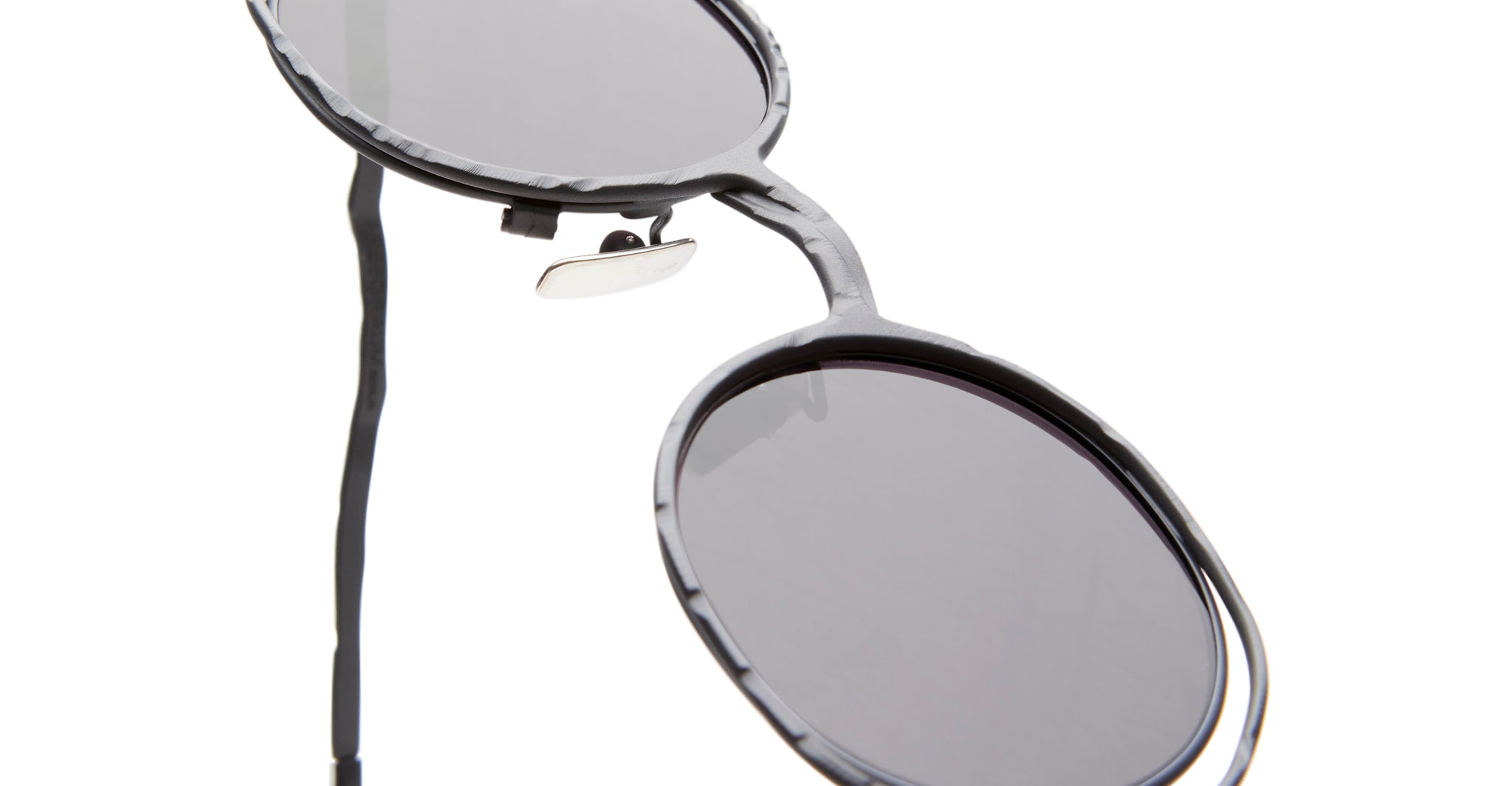 Close-up of Kuboraum H11 round sunglasses with dark lenses and a textured black frame, shown from an angled side view against a white background.