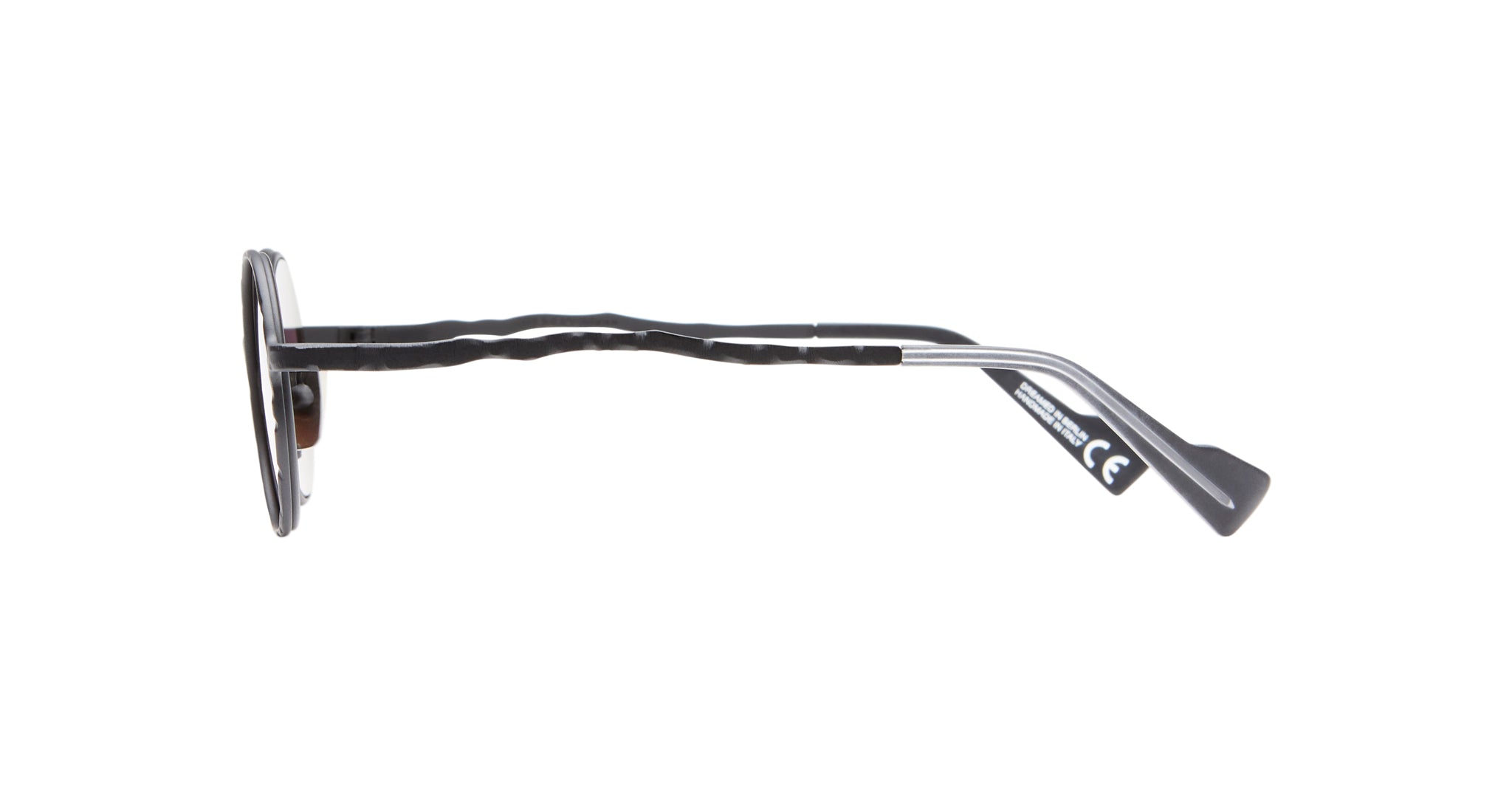 Side view of Kuboraum H11 round eyeglasses with black and silver wavy arms and black temple tips, set against a white background. A small tag with markings appears on the inner right arm.