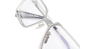 Close-up of Kuboraum H15 rectangular eyeglasses with clear lenses and a sleek silver metal frame, displayed at an angle on a white background.