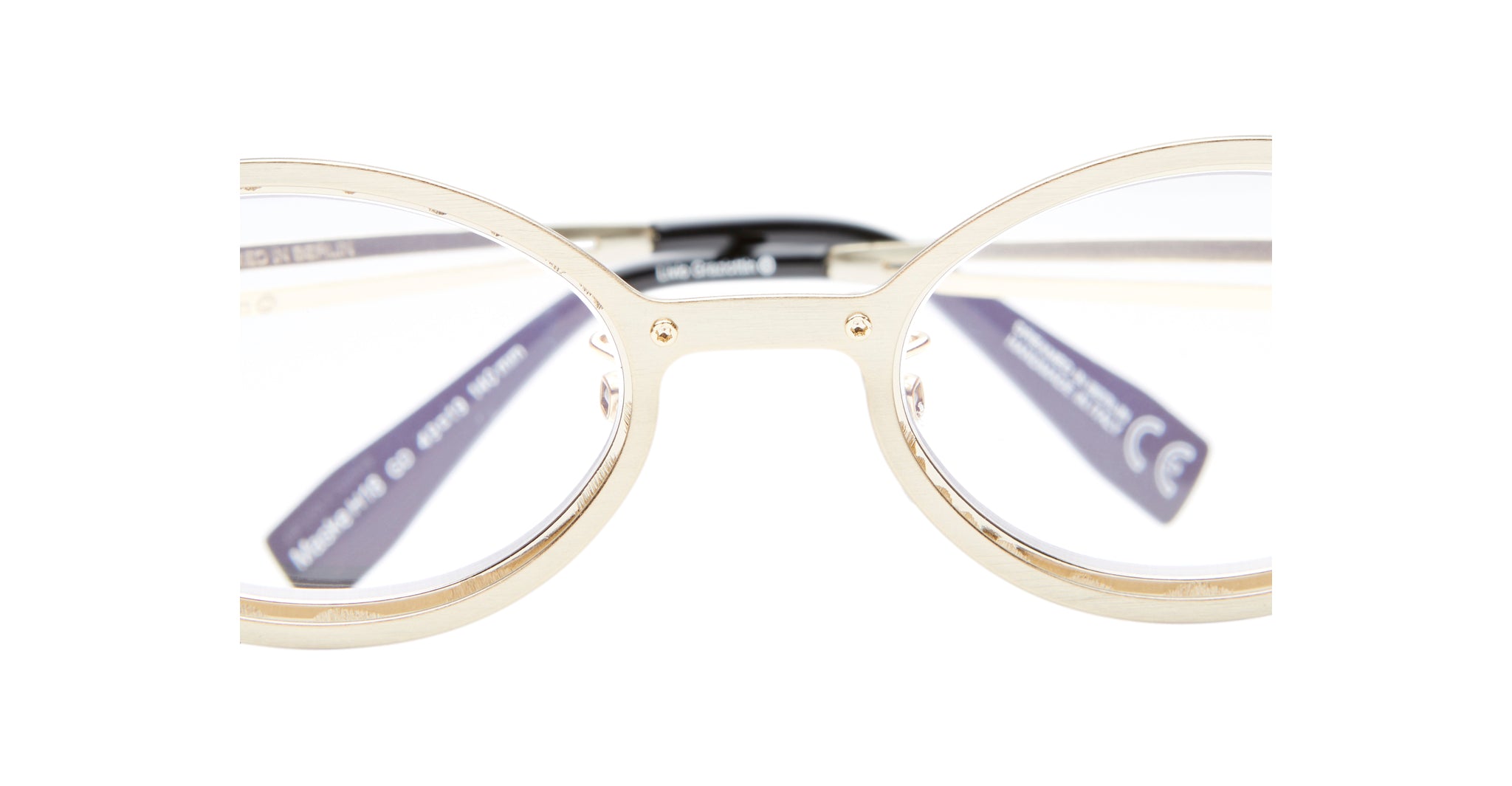 Close-up view of the Kuboraum H18 gold metal eyeglass frames with clear lenses, highlighting the nose bridge and temples; white background.