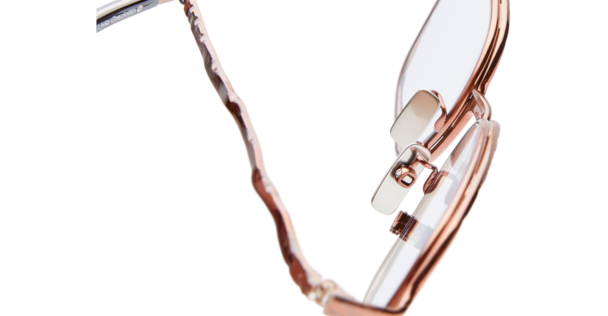 Close-up view of Kuboraum H22 rose gold eyeglasses with clear lenses, featuring wavy textured temples and transparent nose pads, set against a white background.