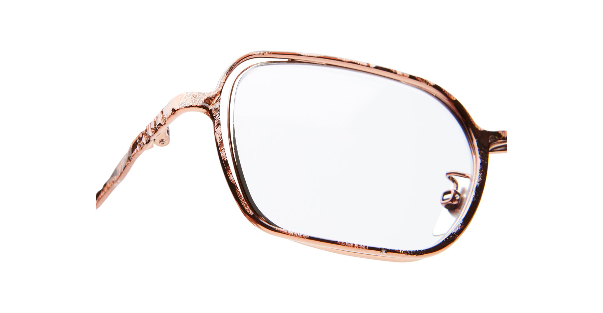 Close-up of Kuboraum H22 eyeglasses featuring a metallic, rose gold rectangular frame with clear lenses and intricate temple detailing, isolated on a white background.