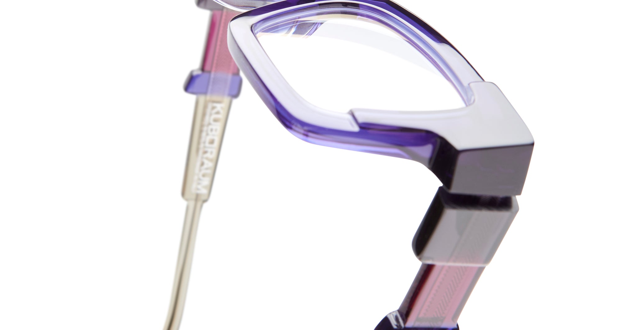 Close-up of Kuboraum I01 eyeglasses, geometric purple and clear frames, metal temple engraved with KUBORAUM.