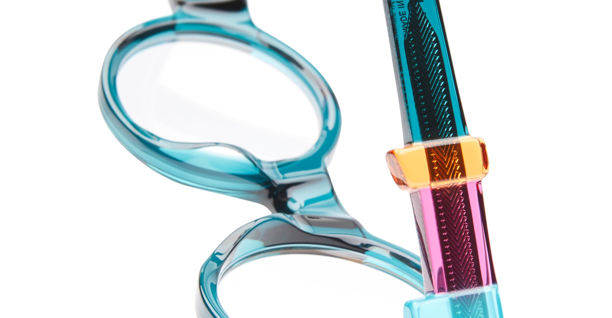 Close-up of Kuboraum I02 transparent blue acetate eyeglasses with pink-orange temples, KUBORAUM branding visible, front view.