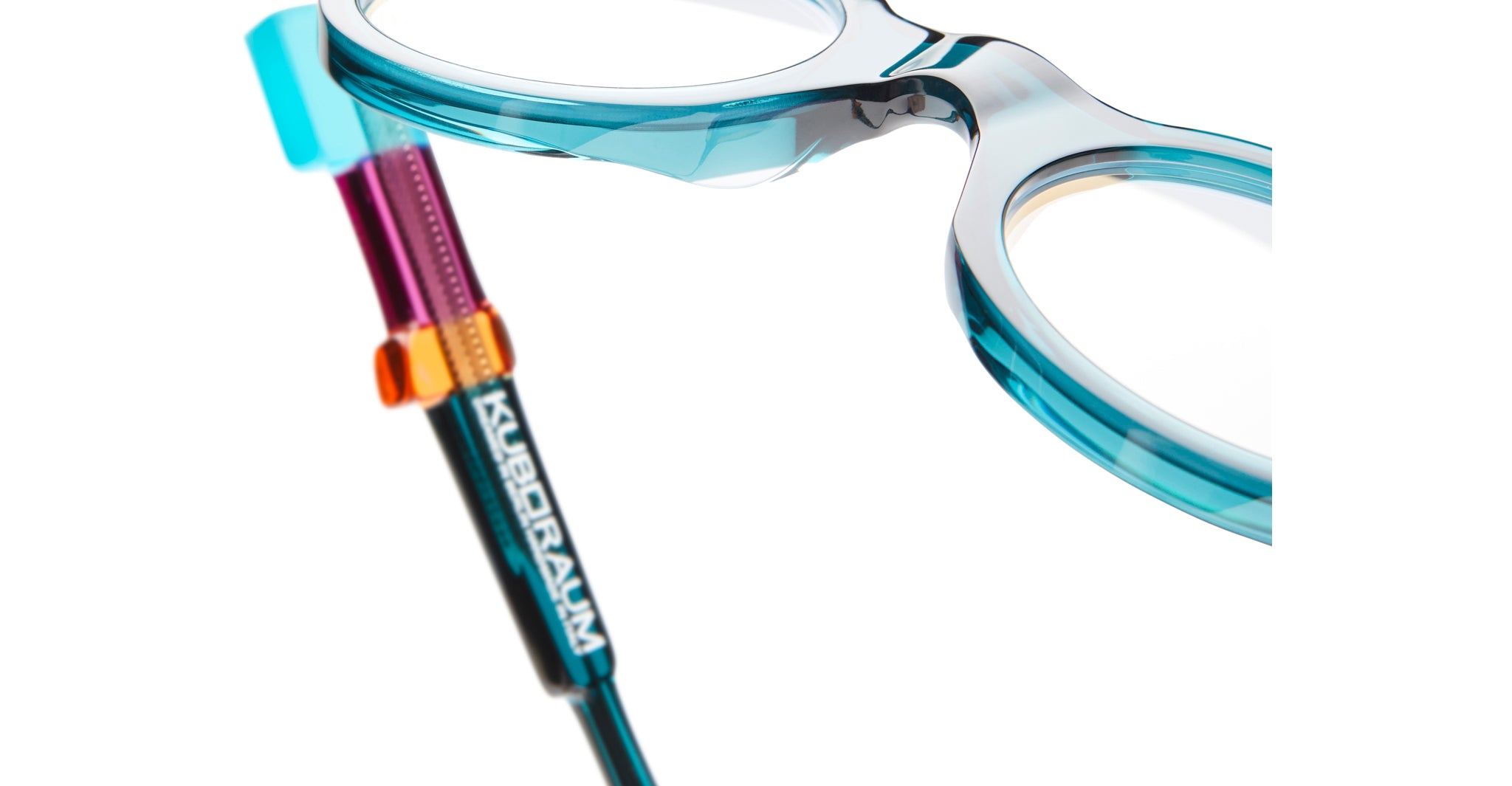 Close-up of Kuboraum I02 eyeglasses with turquoise frames, geometric multicolor temples, and KUBORAUM logo on the arm.