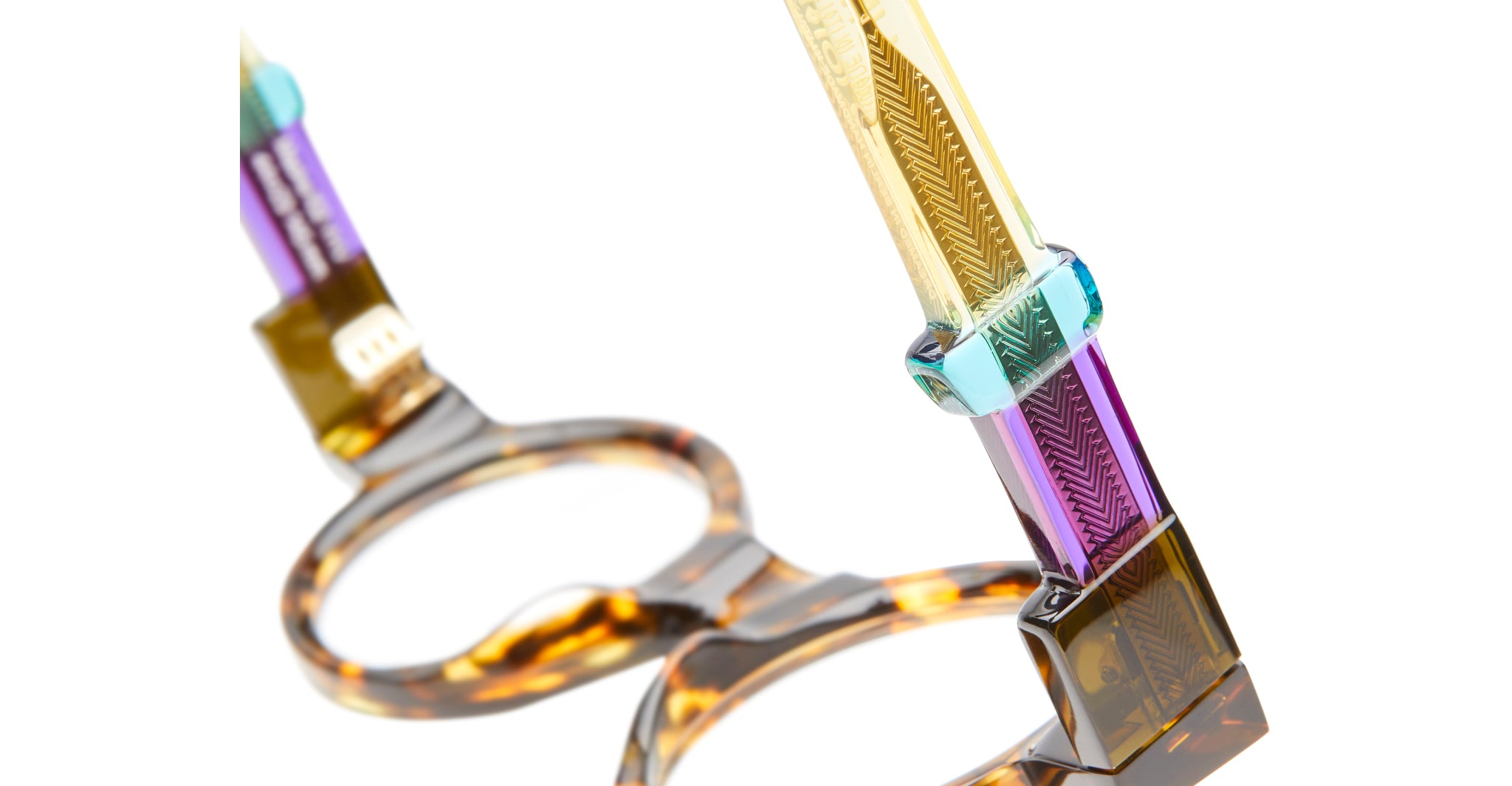 Close-up of Kuboraum I02 eyeglass frames with multicolored translucent acetate temples and etched patterns, viewed from the side.