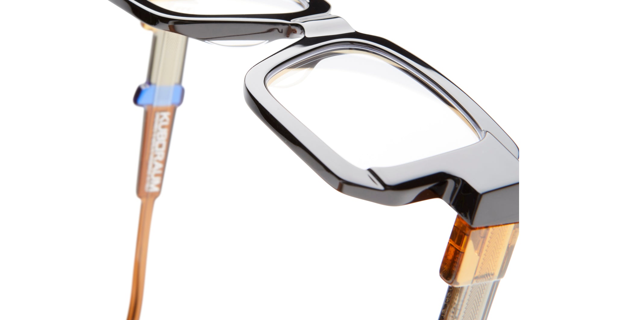 Close-up of KUBORAUM I03 eyeglasses showing thick angular frames and KUBORAUM logo on the temple, viewed from the side.