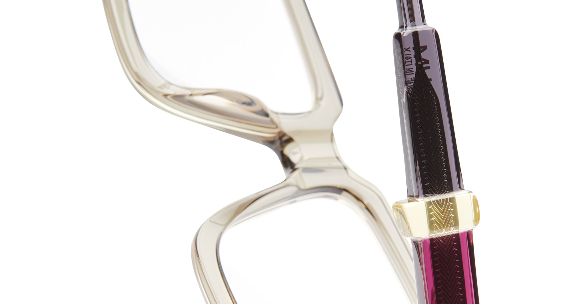 Close-up of KUBORAUM Kuboraum I03 clear eyeglass frames and a gold and dark purple fountain pen, front angle.