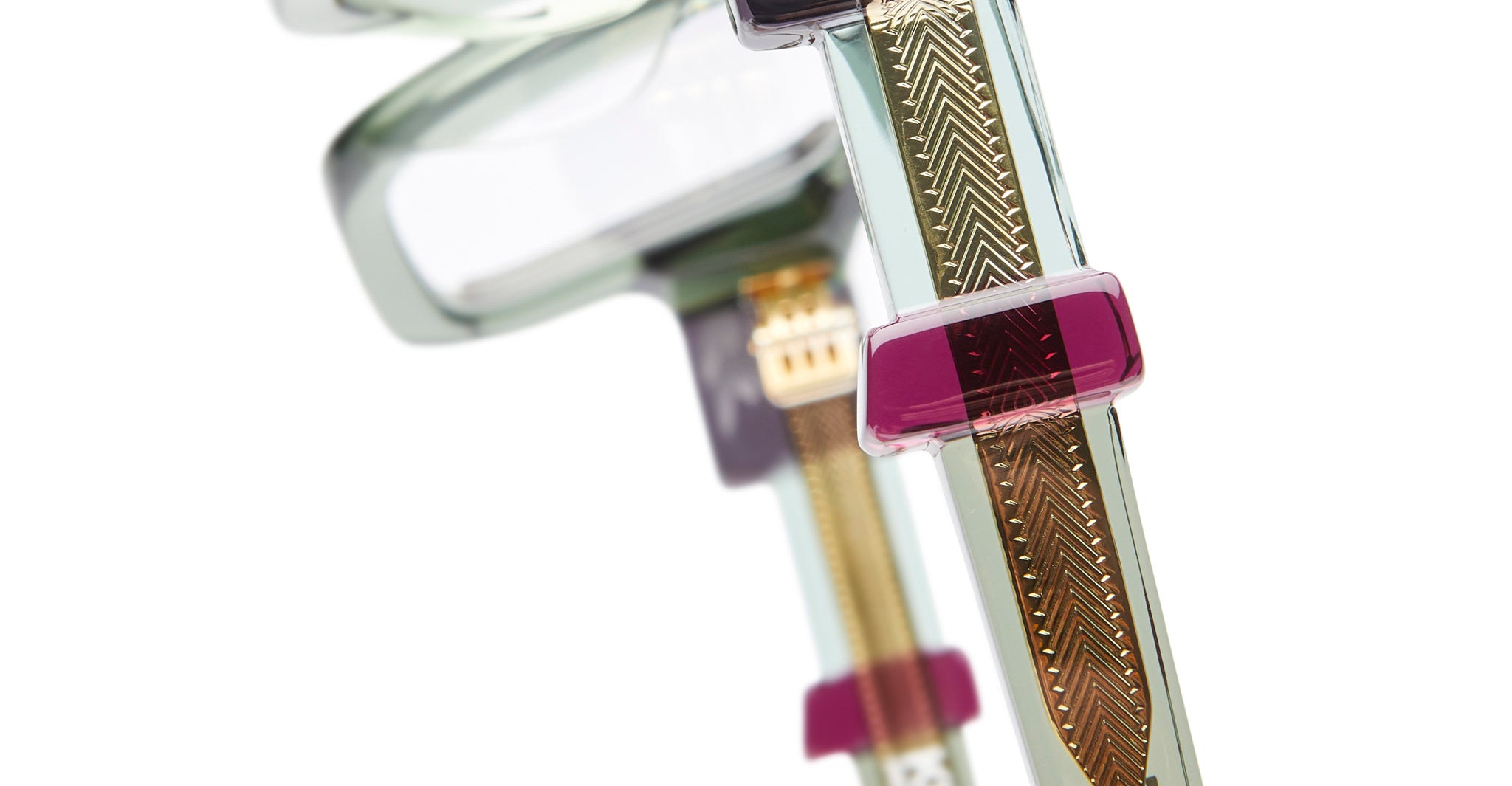 Close-up view of KUBORAUM I03 eyeglasses featuring translucent frames, gold-green patterned temples, and purple acetate accents.