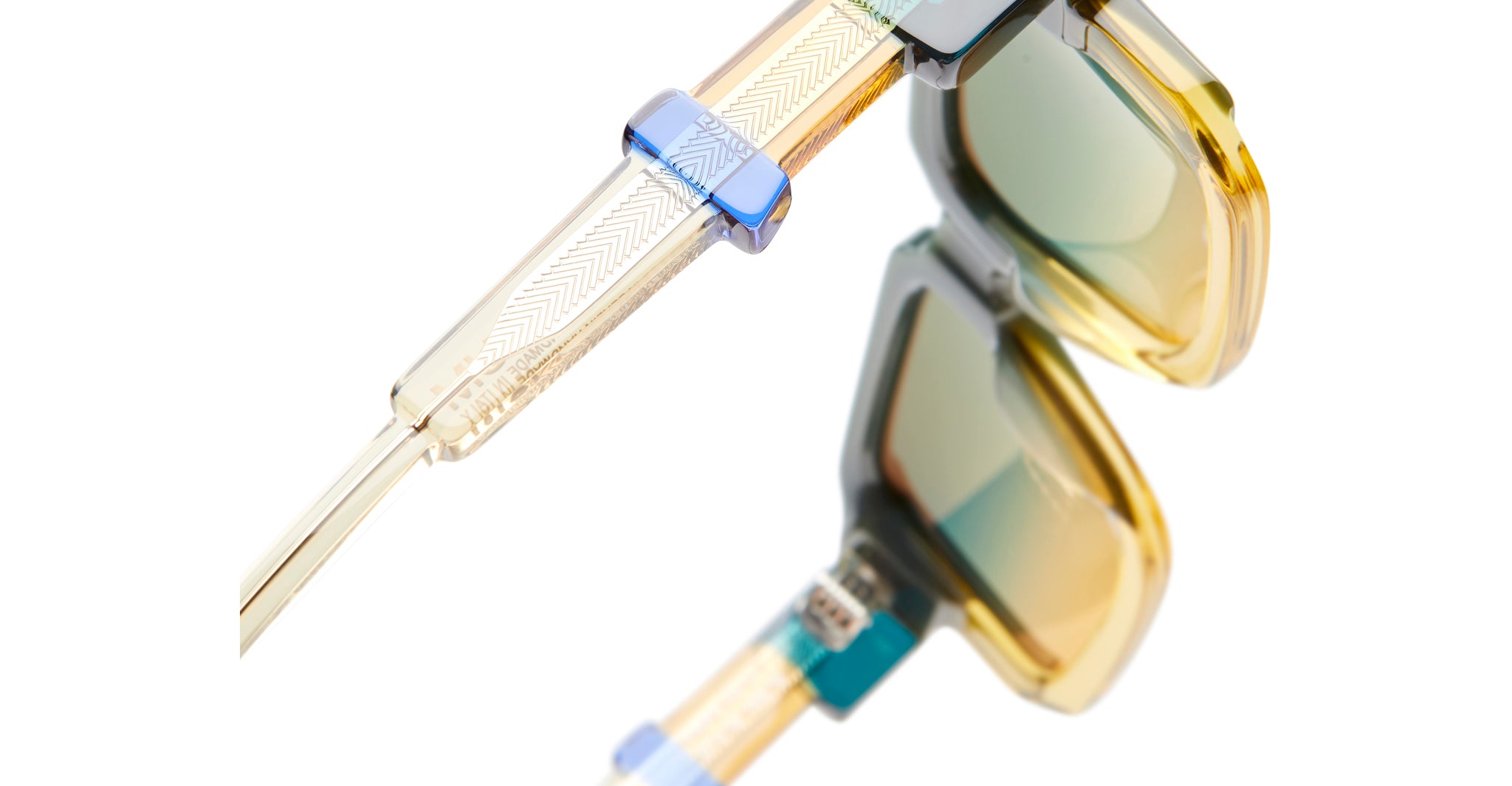 Close-up of KUBORAUM I03 sunglasses showing vibrant yellow and blue frames, viewed from above. Brand and model visible.