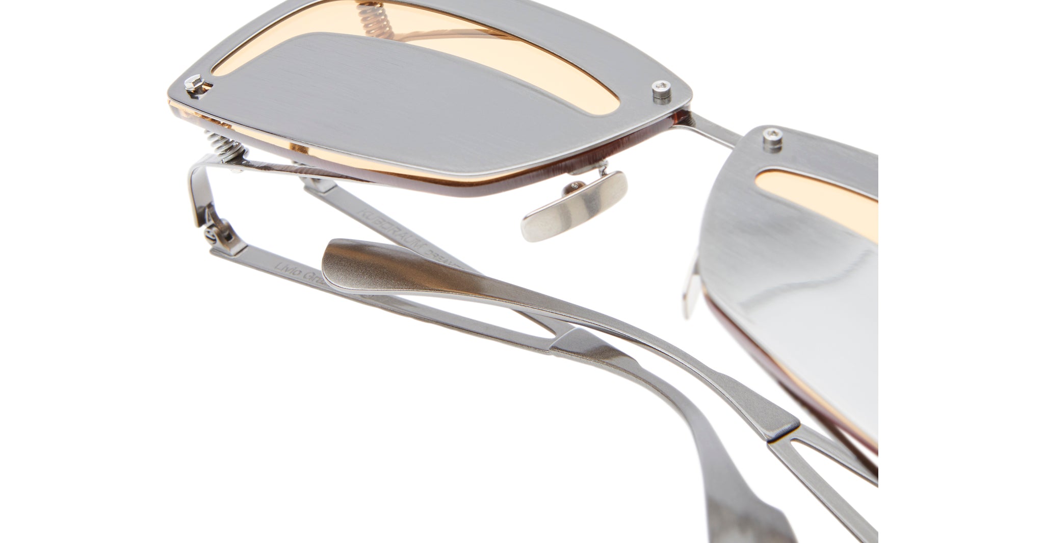 Close-up of Kuboraum I50 eyeglasses with a unique angular metal frame and light brown lenses, highlighting the intricate hinge and side details against a white background.