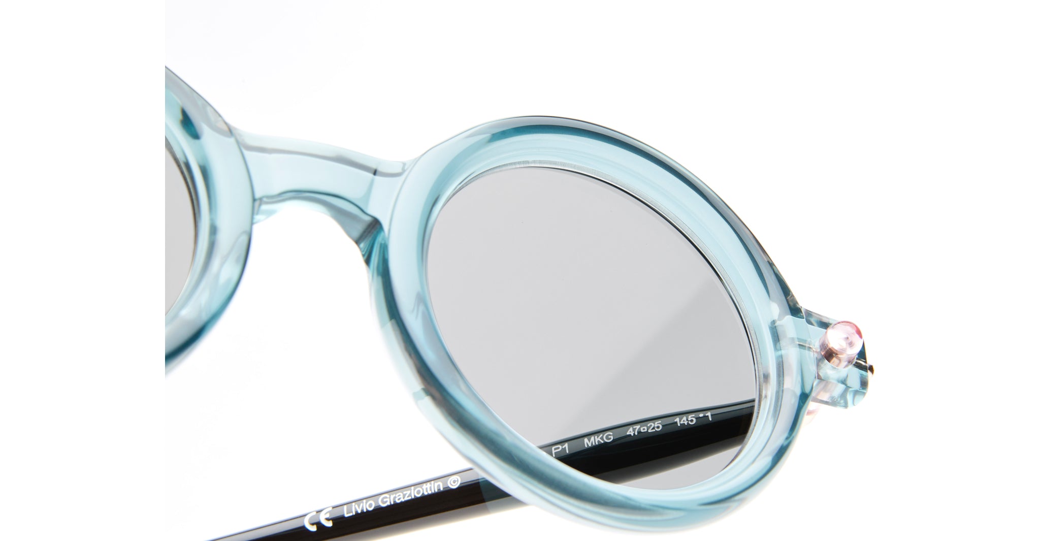 Close-up of Kuboraum P1: round, translucent light blue eyeglass frames with silver hinges and dark temple arms, shown partially against a white background.