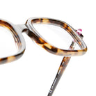 Close-up of Kuboraum P2 tortoiseshell square eyeglass frames featuring a pink stud detail on the top corner, set against a white background.