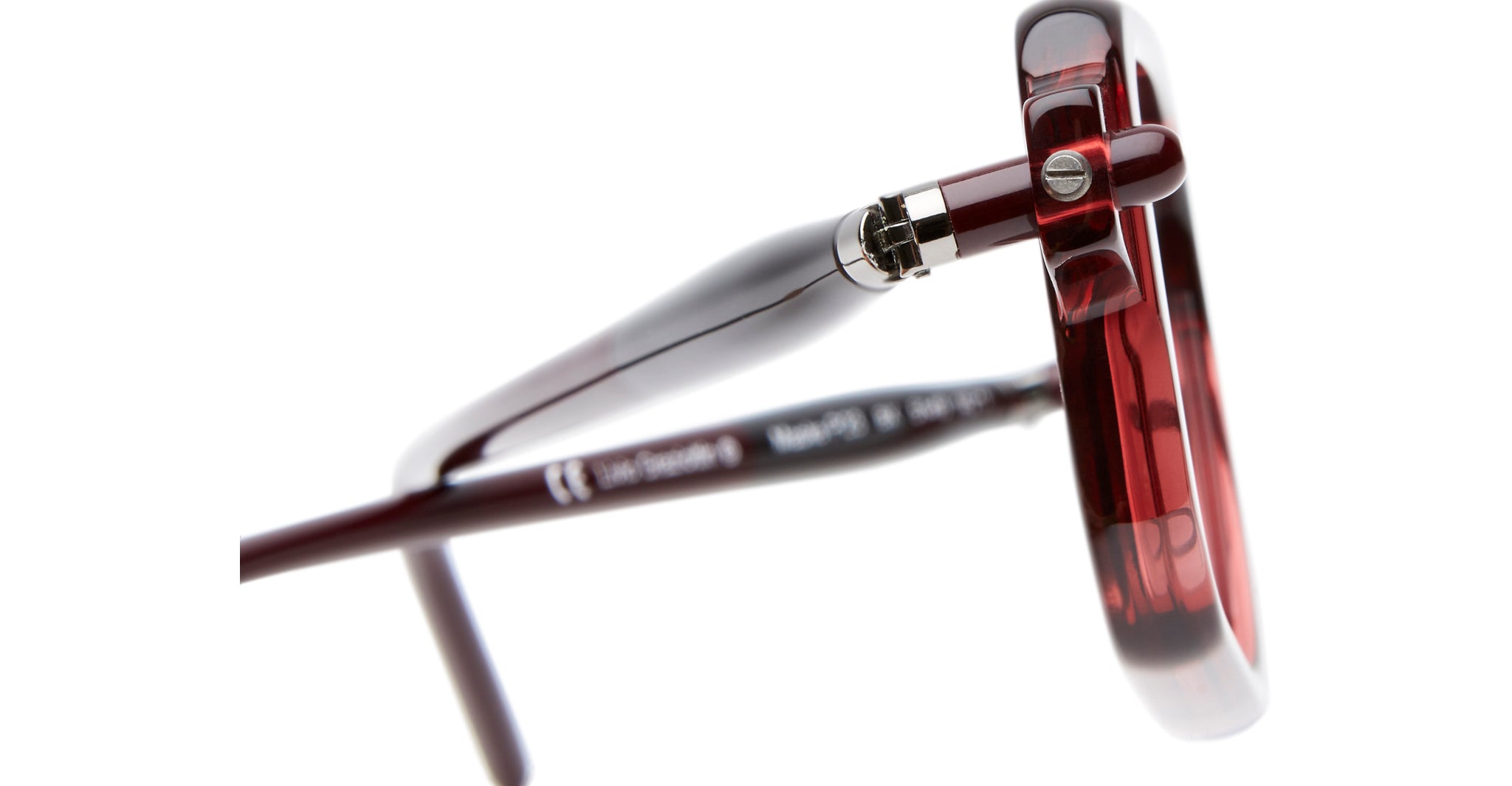 Close-up view of the hinge and arm of the Kuboraum P23 dark red eyeglasses, highlighting the glossy frame finish and detailed metal hinge mechanism.