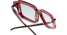 Close-up of Kuboraum P23 eyeglasses featuring red and transparent square frames with thin dark arms, clear lenses, and a glossy finish, displayed on a white background.