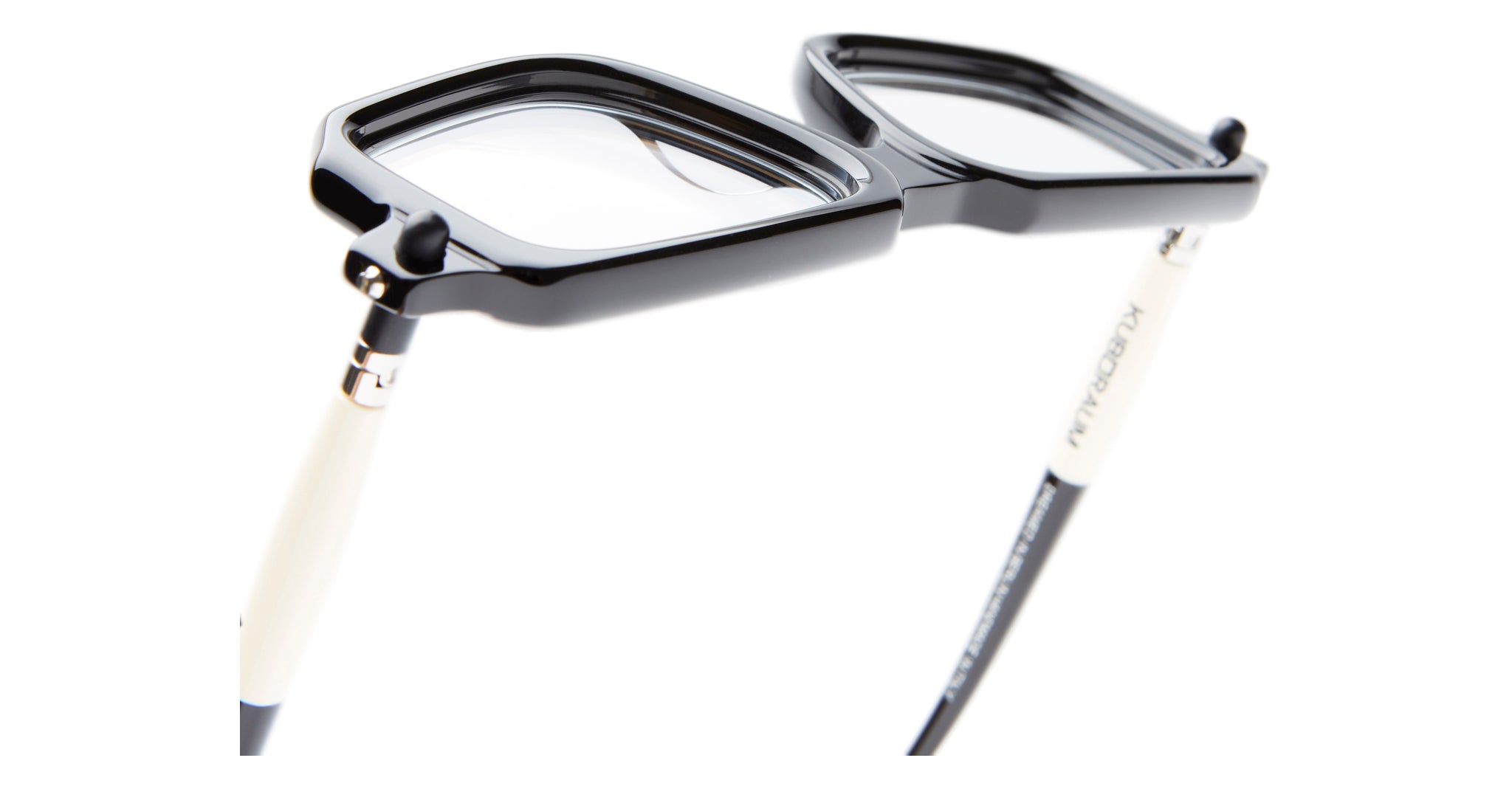 A close-up of Kuboraum P23 black and white eyeglasses featuring a unique flip-up lens design, set against a white background.