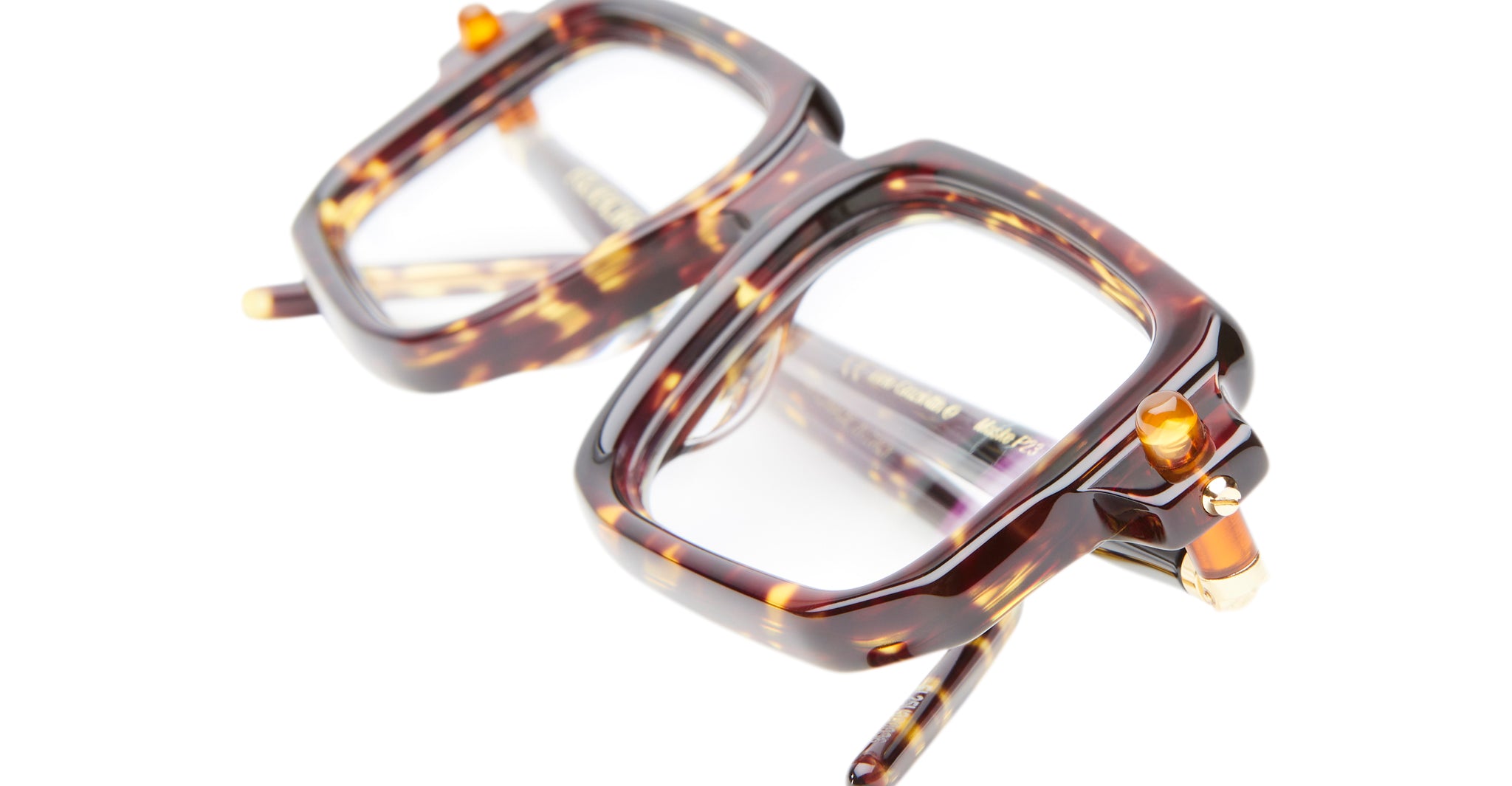 Close-up of the Kuboraum P23 eyeglasses—chunky, rectangular frames in brown tortoiseshell with gold accents, displayed on a white background.