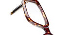 Close-up of the corner of Kuboraum P23 eyeglasses featuring a brown and yellow tortoiseshell pattern, set against a white background.