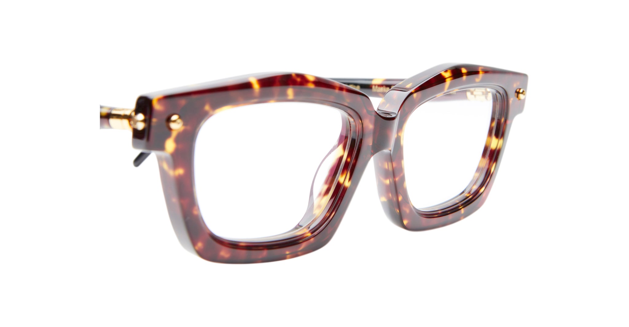 Close-up of Kuboraum P25 eyeglasses featuring thick brown tortoiseshell frames, gold hinge accents, and clear lenses, set against a white background.