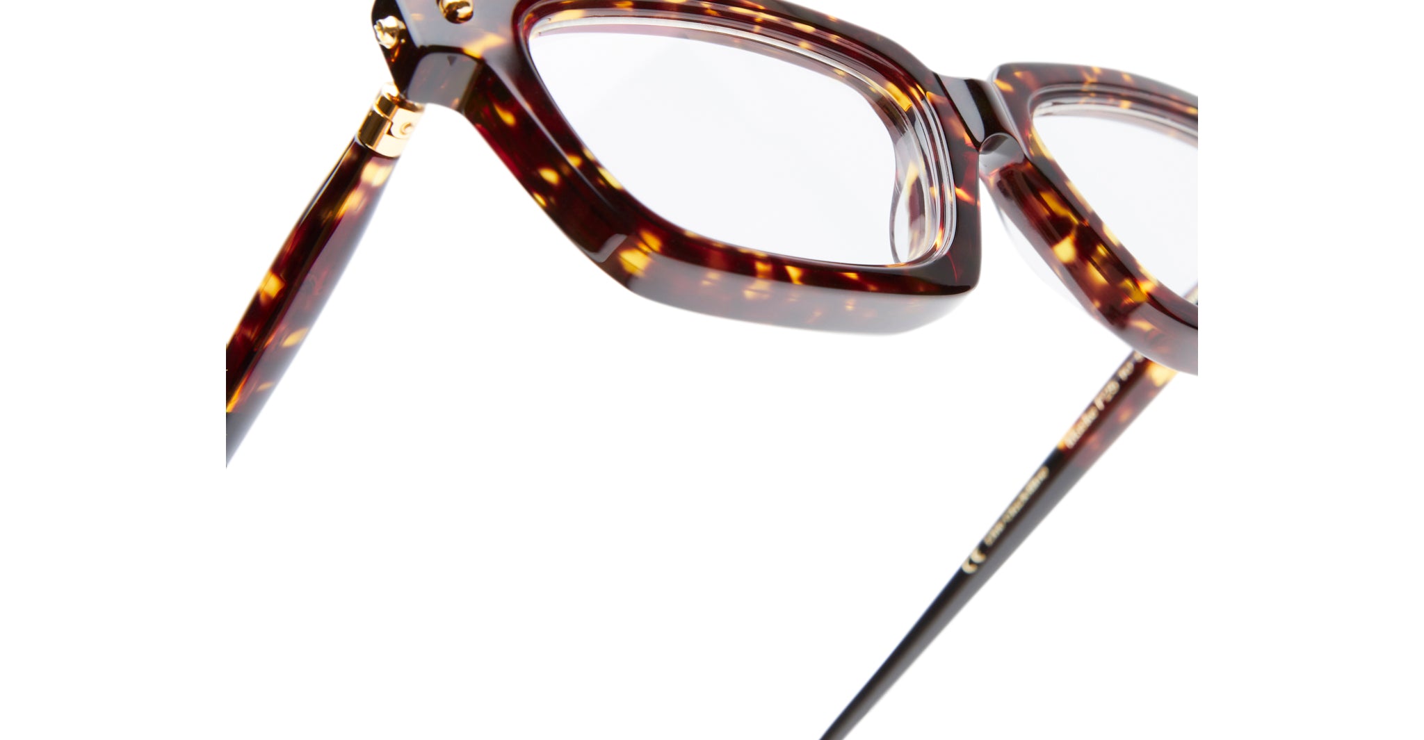 Close-up of Kuboraum P25 tortoiseshell eyeglasses featuring rectangular lenses and gold hinge details, set against a white background.