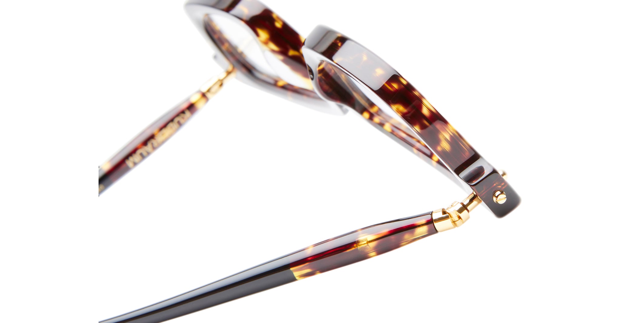 Close-up of Kuboraum P25 tortoiseshell eyeglasses with gold accents on the hinges and arms, viewed from the side and slightly above against a white background.