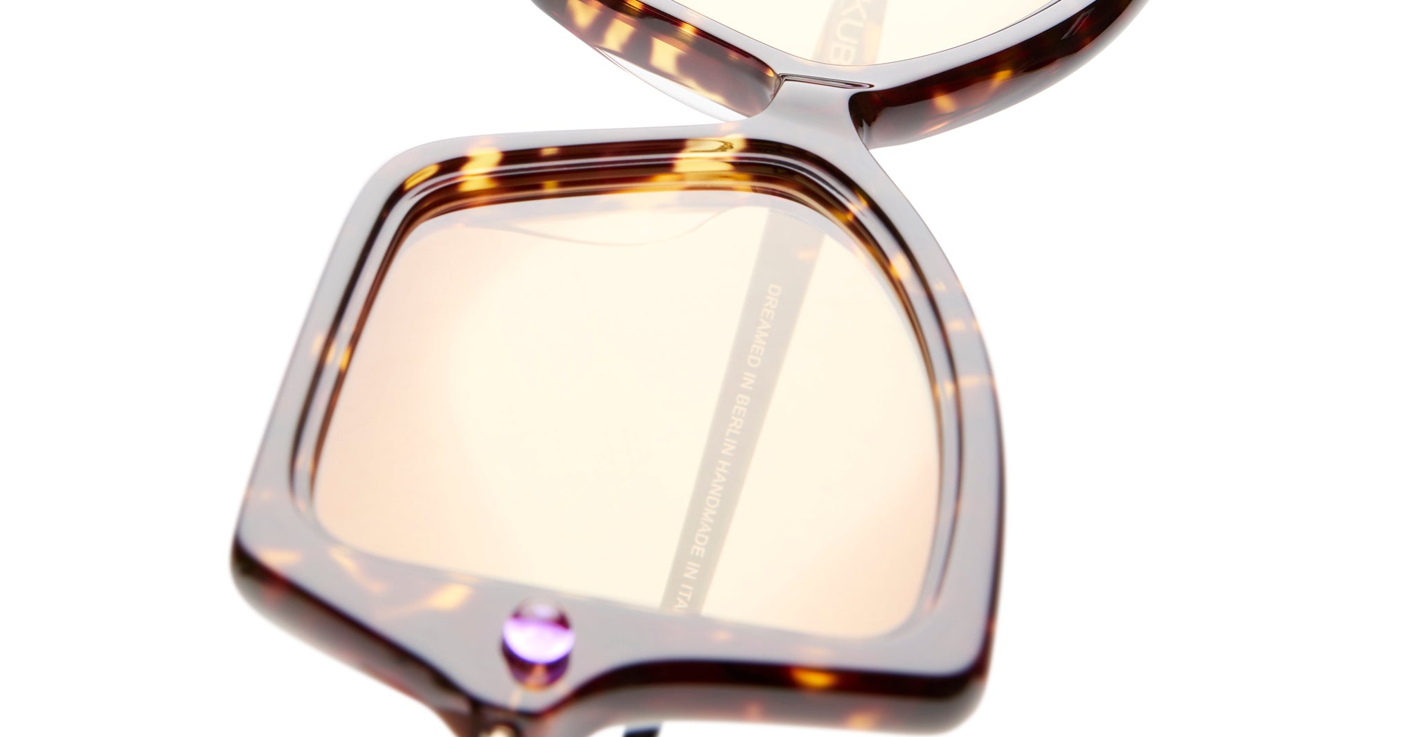 Close-up of Kuboraum P30 sunglasses by KUBORAUM, showing oversized square tortoiseshell frame, amber lenses, and purple detail.