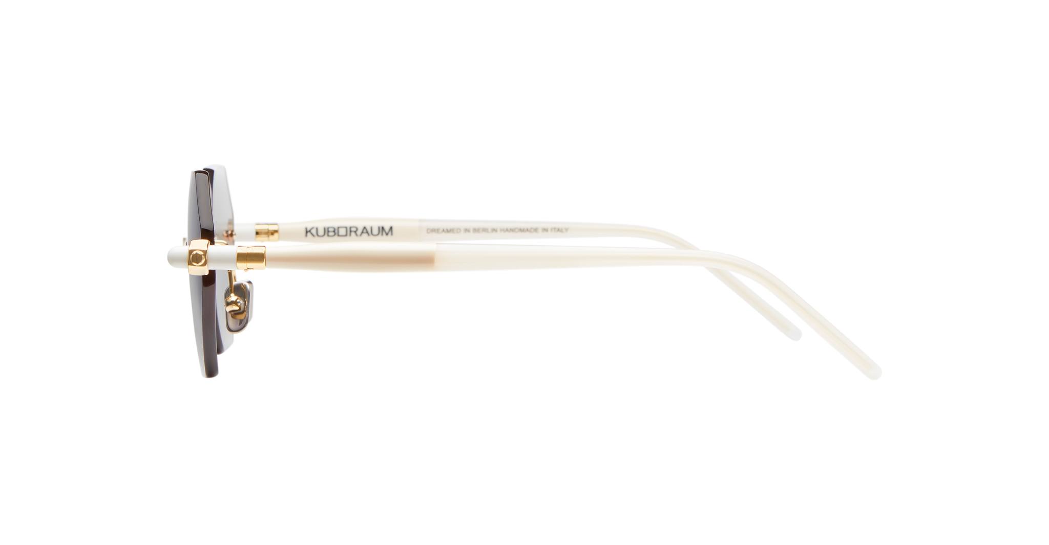Side view of the Kuboraum P54 white sunglasses with gold accents and dark lenses, featuring the KUBORAUM brand name on the arm, set against a plain white background.