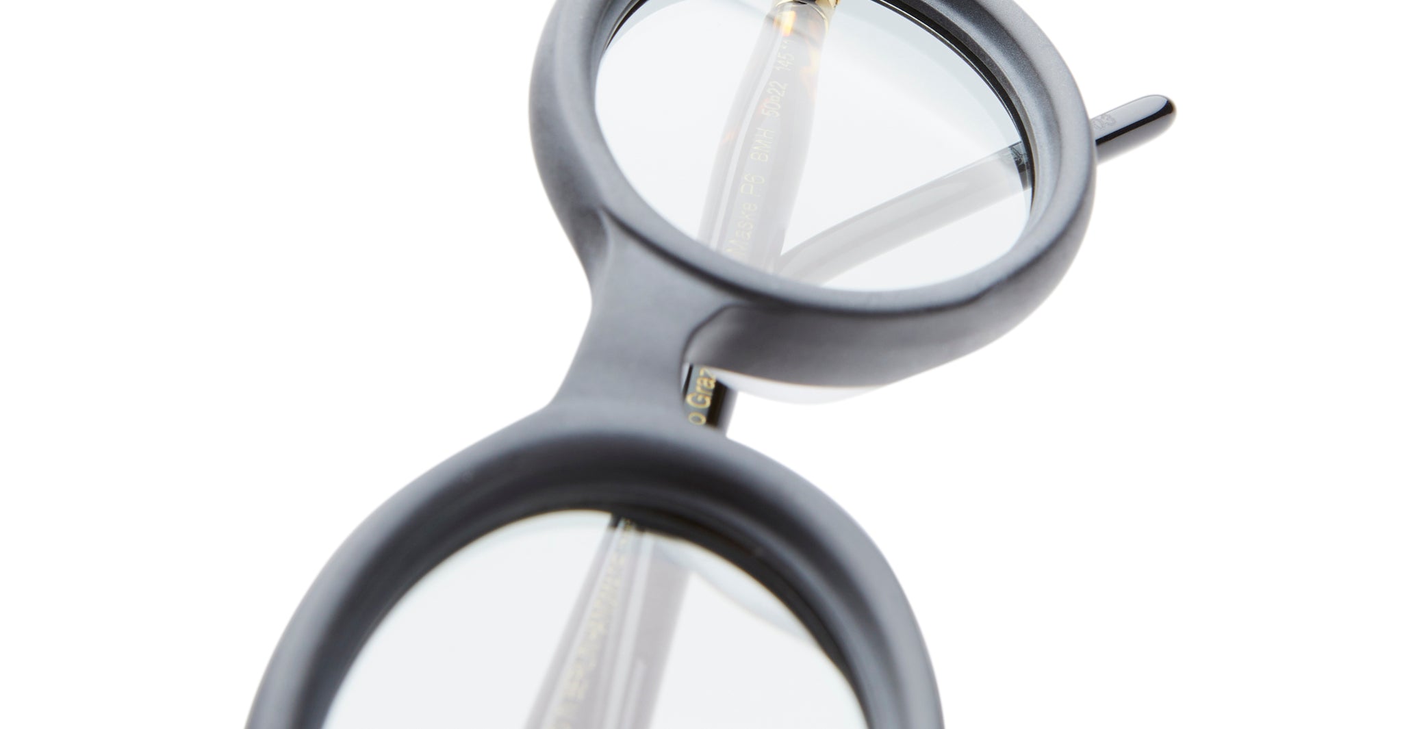 Close-up of Kuboraum P6 round black eyeglass frames with clear lenses, shown on a white background. Focus is on the bridge and part of the left temple arm.