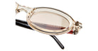 Close-up of Kuboraum P6 round eyeglasses featuring transparent beige frames, slightly tinted lenses, and visible black and red temple arms with text printed on the inner side.