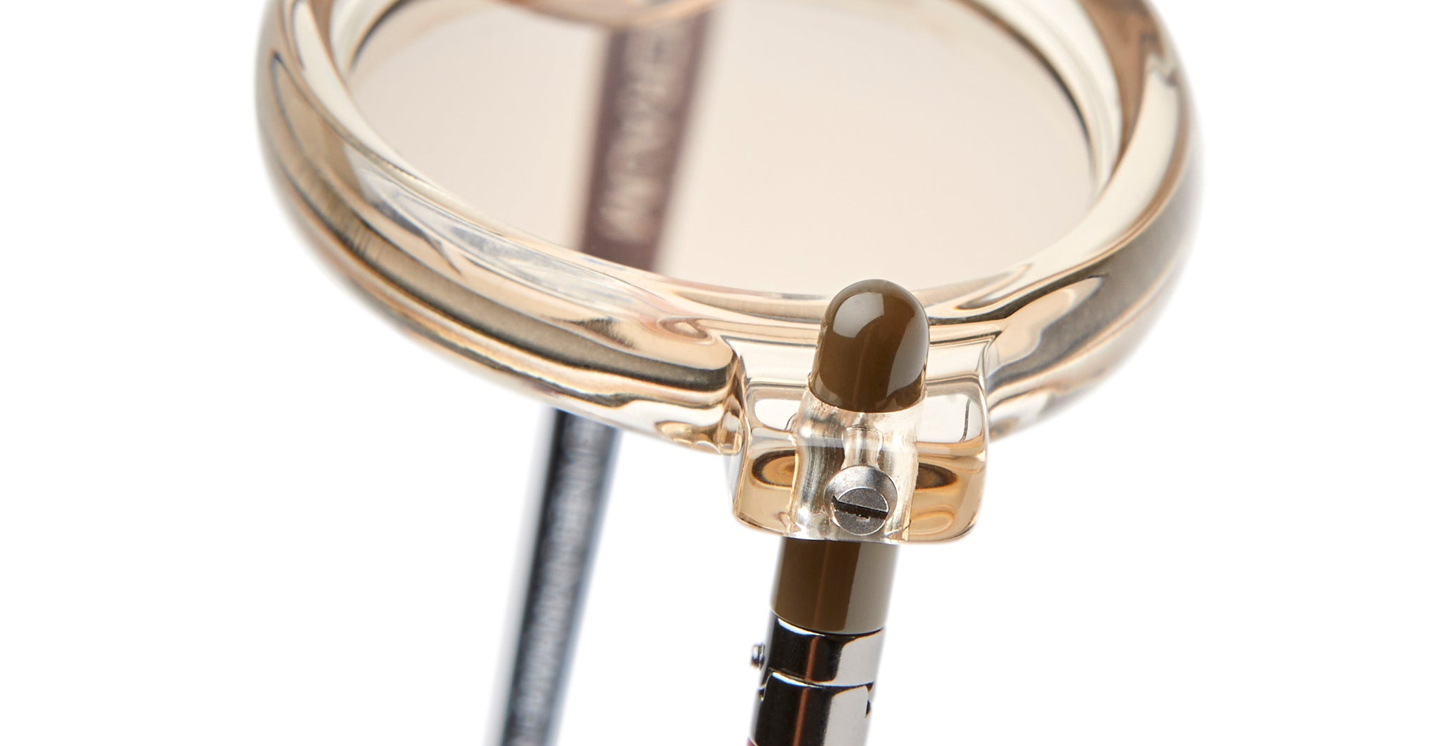 Close-up of Kuboraum P6 eyeglasses highlighting the hinge where the temple arm meets the translucent beige frame, with a blurred lens and visible screw detail.