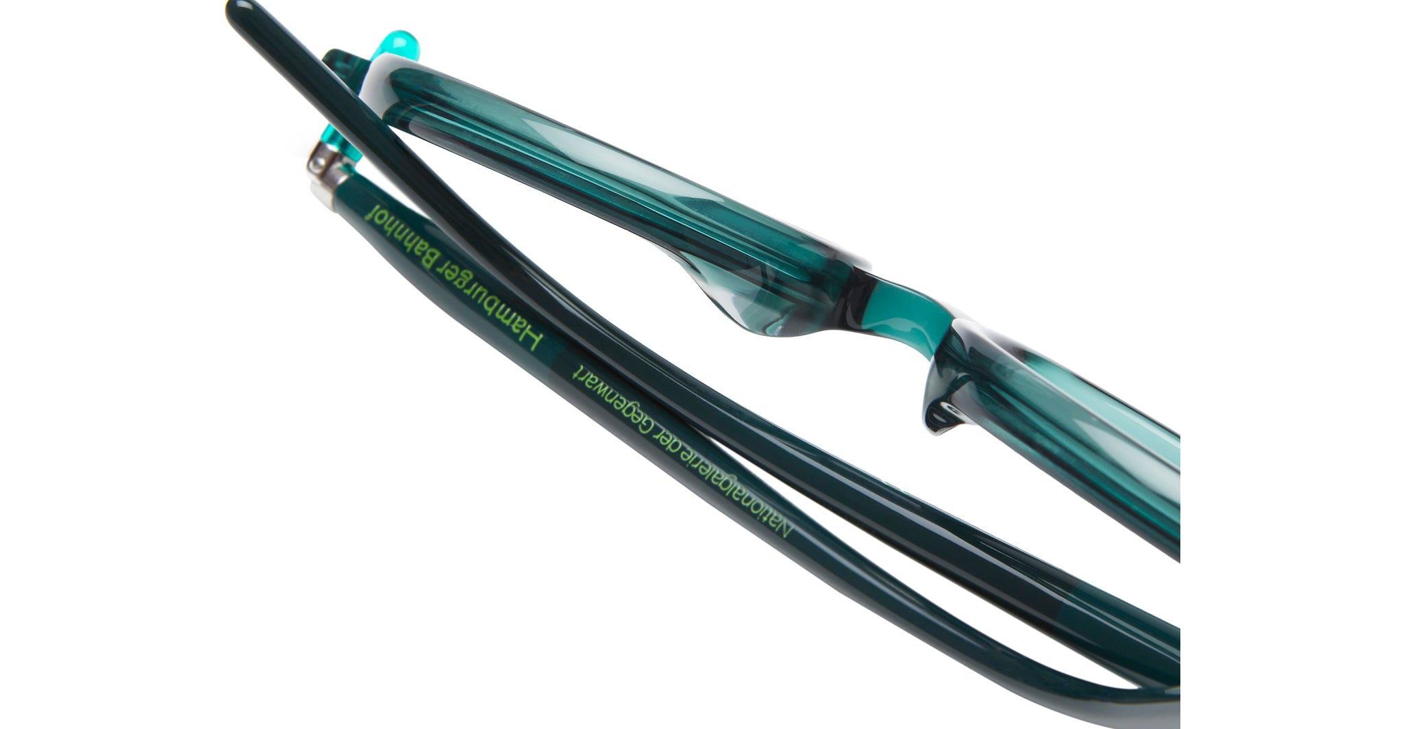 Close-up of teal and black eyeglasses with Nationalgalerie der Gegenwart Hamburger Bahnhof written in green text on the arm. The background is white.