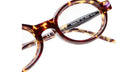 Close-up of Kuboraum P6 round tortoiseshell eyeglasses with brown and amber patterns. Model details and measurements are visible on the inner arm. Set against a white background.