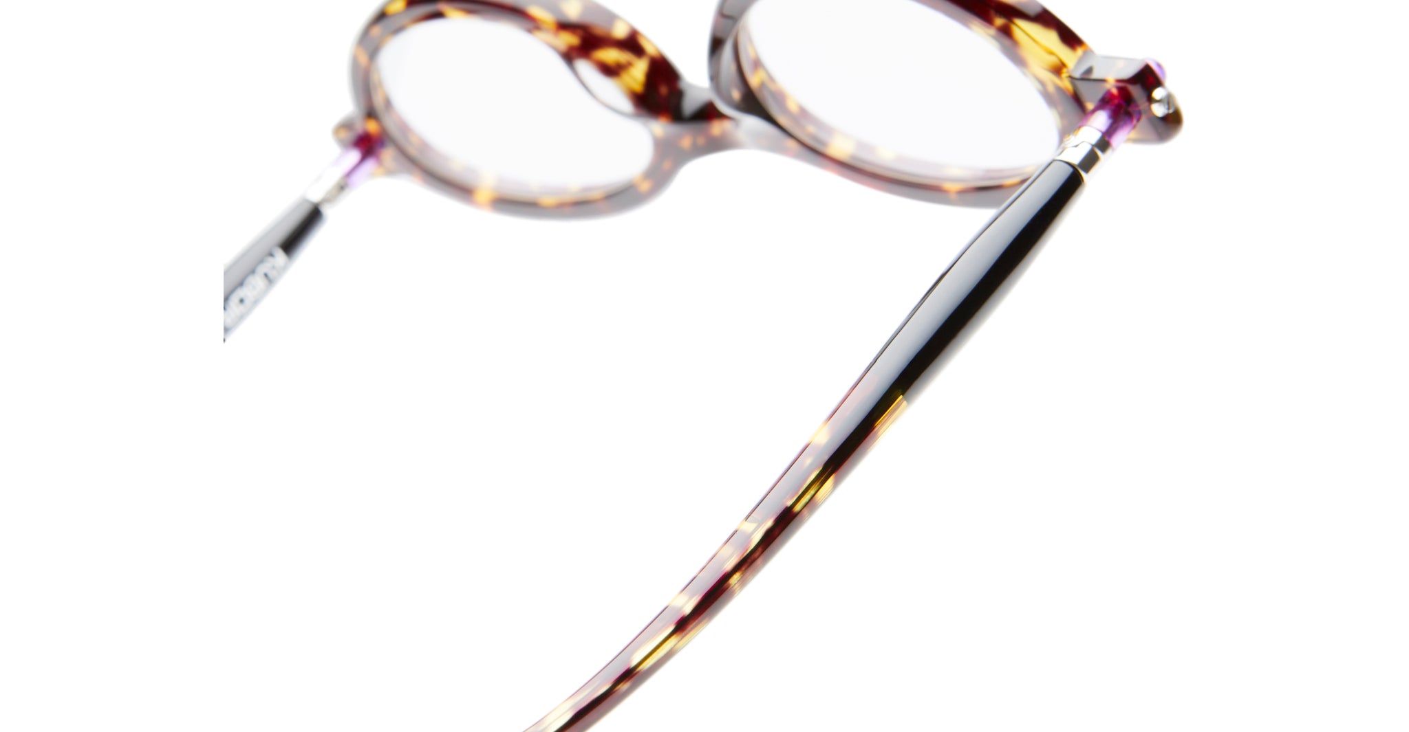 A close-up of the Kuboraum P6 tortoiseshell-patterned eyeglasses highlights the frame and temple arm against a white background.