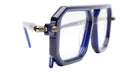 Close-up of Kuboraum P8: oversized geometric eyeglasses with thick angular blue frames, clear lenses, and temples featuring blue with beige accents near the hinges. Retro and bold design.