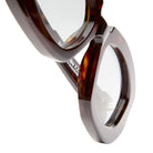 Close-up of Kuboraum X23 tortoiseshell round eyeglasses with transparent lenses on a white background, highlighting the frame and hinge details.