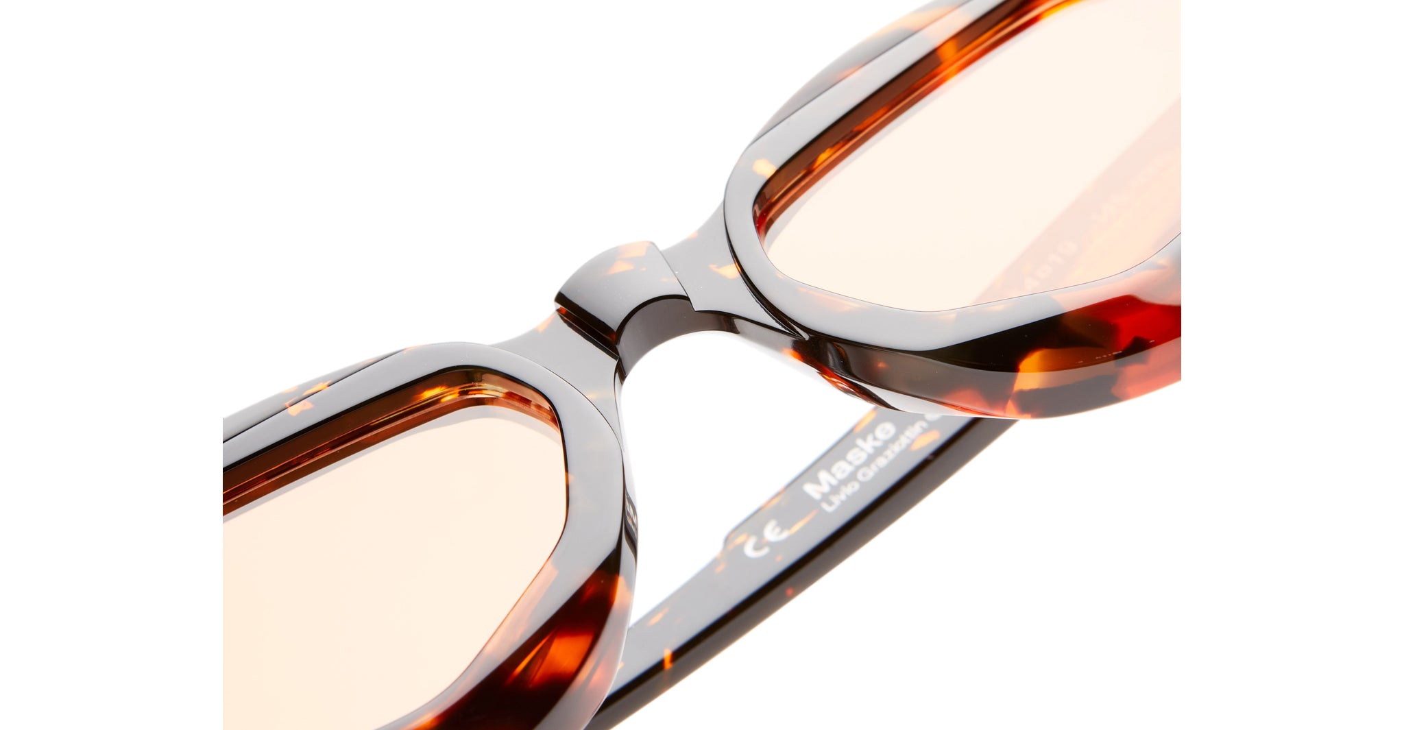 Close-up of Kuboraum Y8 tortoiseshell eyeglass frames with light brown lenses, featuring the bridge and hinges, set against a white background.
