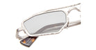Close-up of Kuboraum Z23 sunglasses featuring an irregular, angular silver metal frame and gray-tinted lenses. A visible tag is attached to one arm, set against a white background.