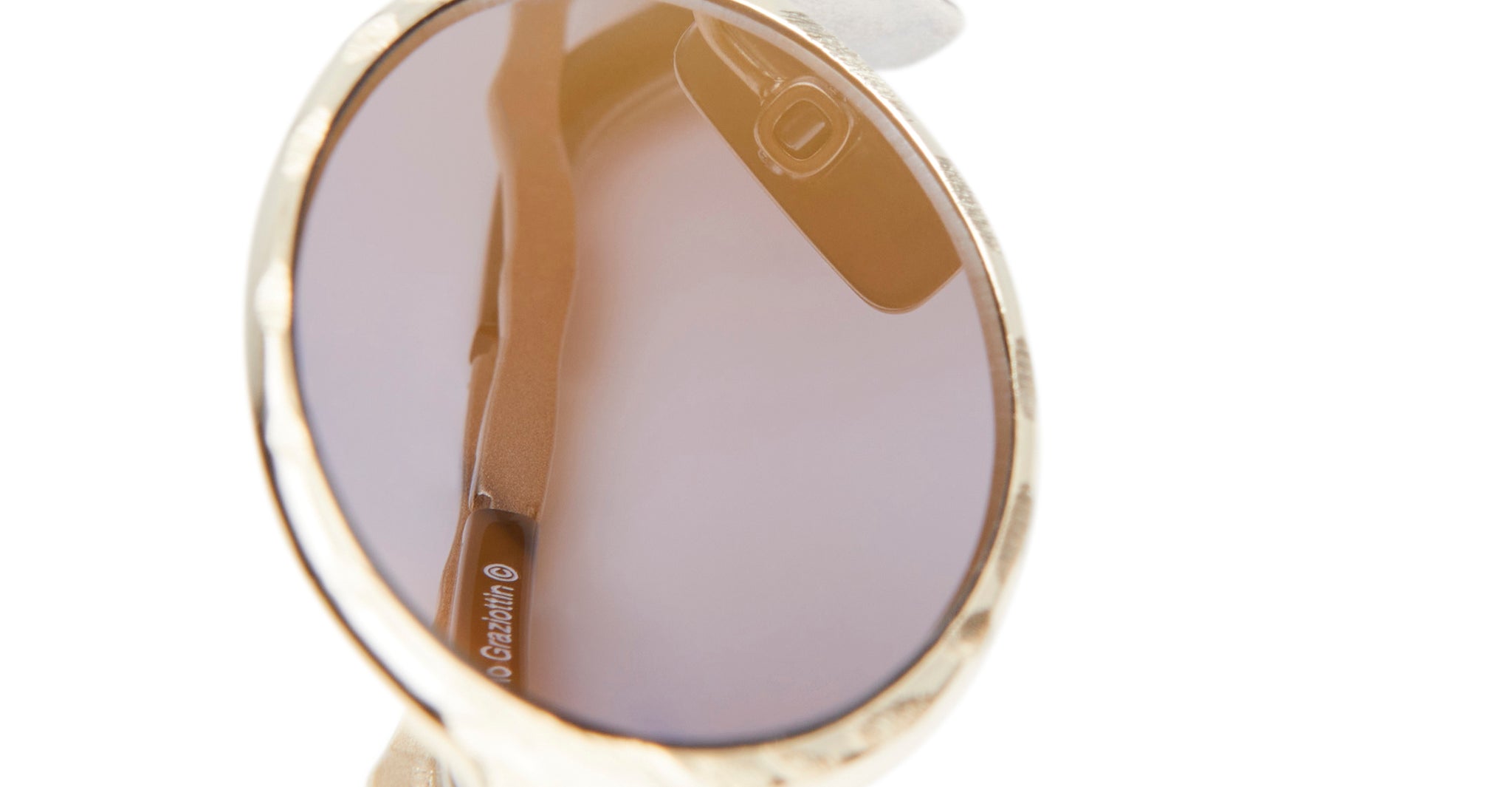 Close-up of Kuboraum Z24 round sunglasses with gold frames and brown-tinted lenses, showing the inner side of one arm against a white background. The brand name appears faintly on the arm.