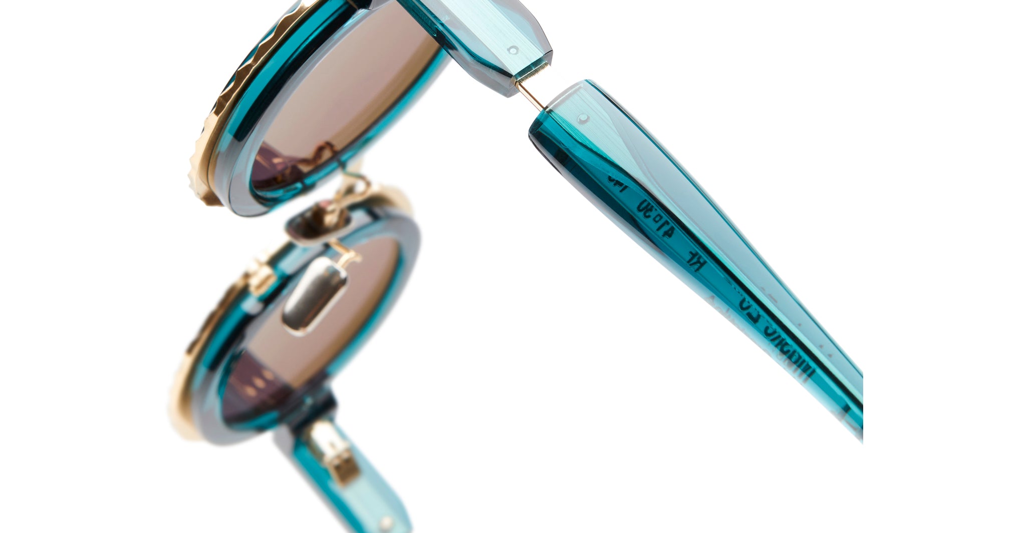 Close-up of KUBORAUM Z3 round sunglasses showing blue translucent frames, gold accents, and engraved text on the hinge.