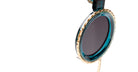 Close-up of Kuboraum Z3 sunglasses lens with round, dark tint and gold and teal rim, viewed from the front.