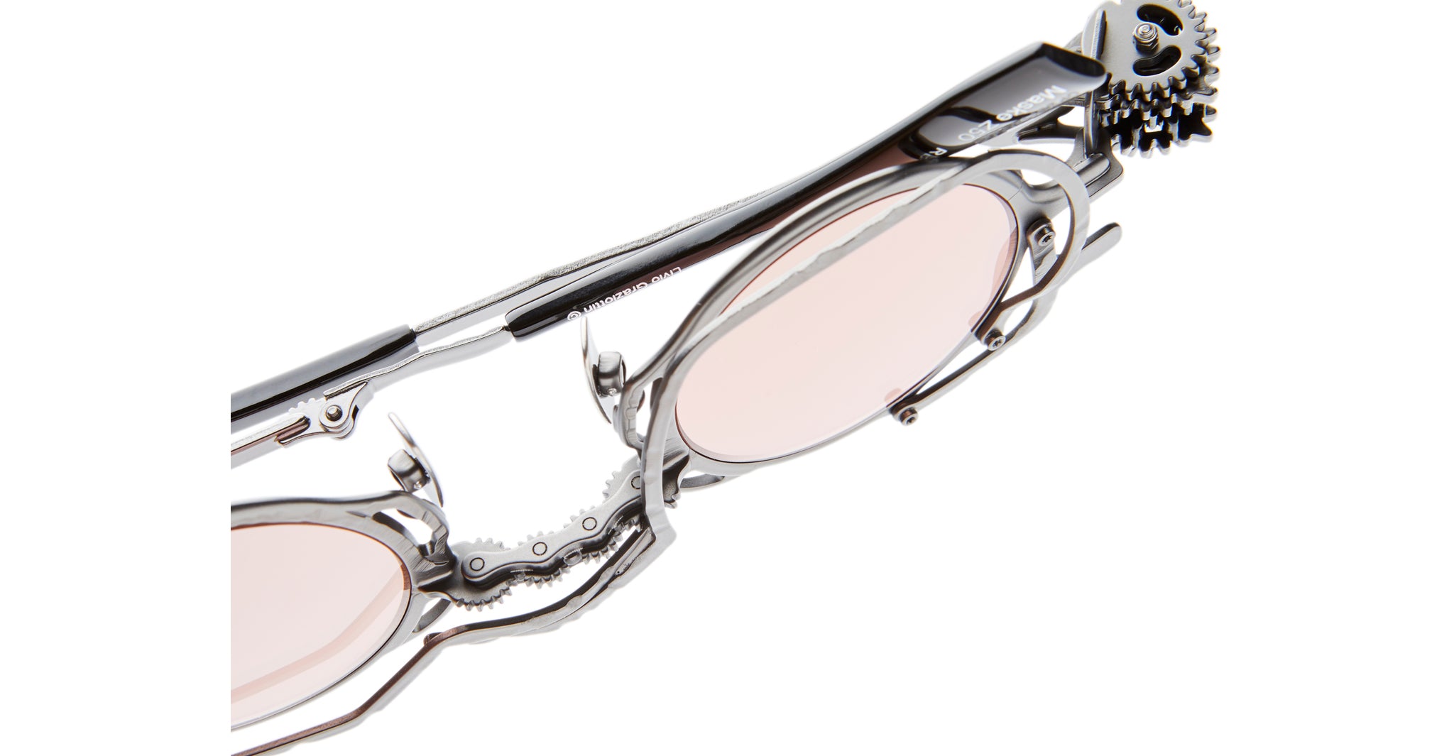 Close-up of Kuboraum Z50: futuristic silver eyeglasses with light pink lenses and intricate mechanical gear details on the temples, giving a steampunk-inspired look.