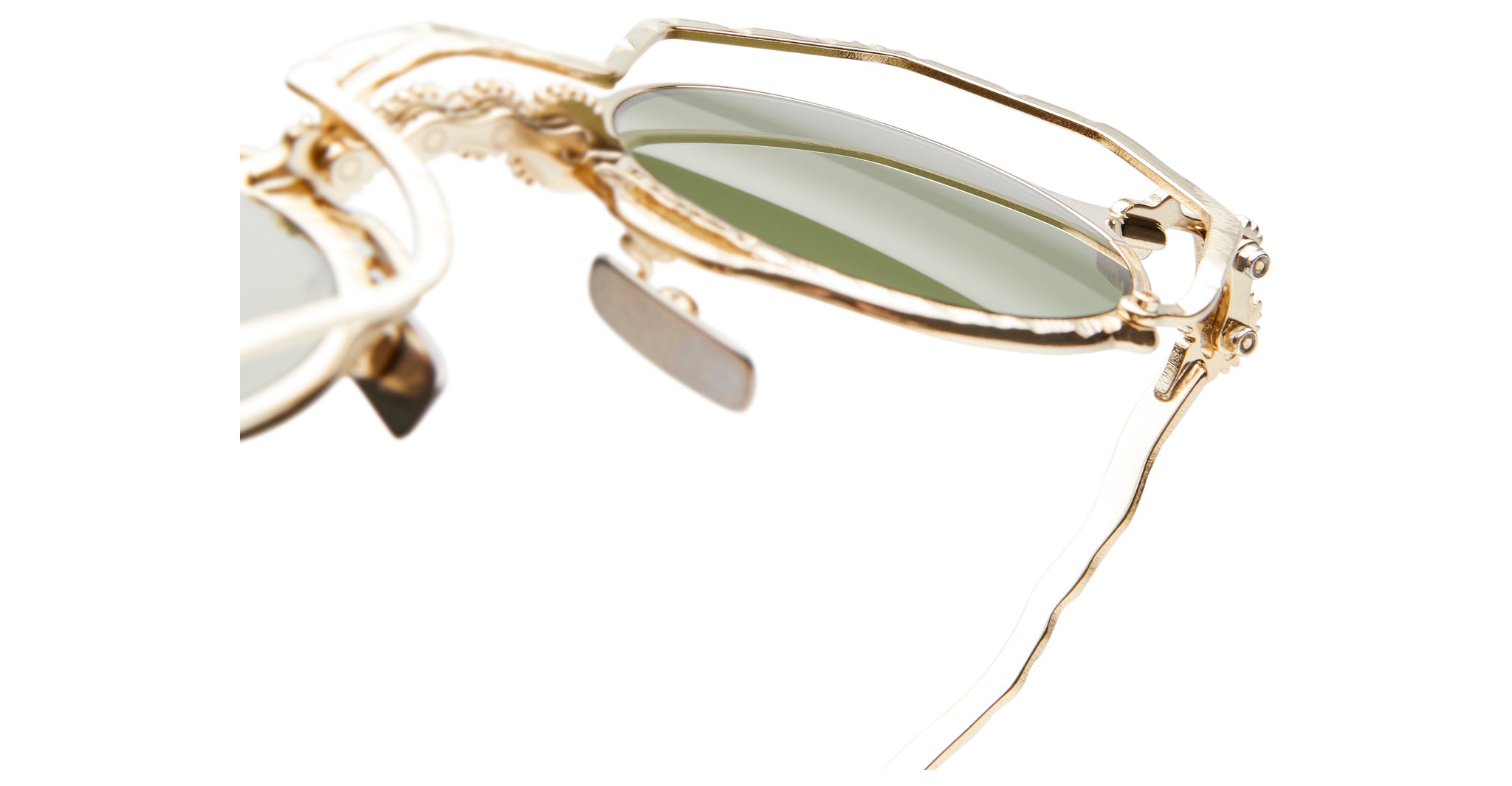 Close-up of Kuboraum Z50 sunglasses by KUBORAUM, featuring a gold frame, green-tinted lenses, and ornate detailing.