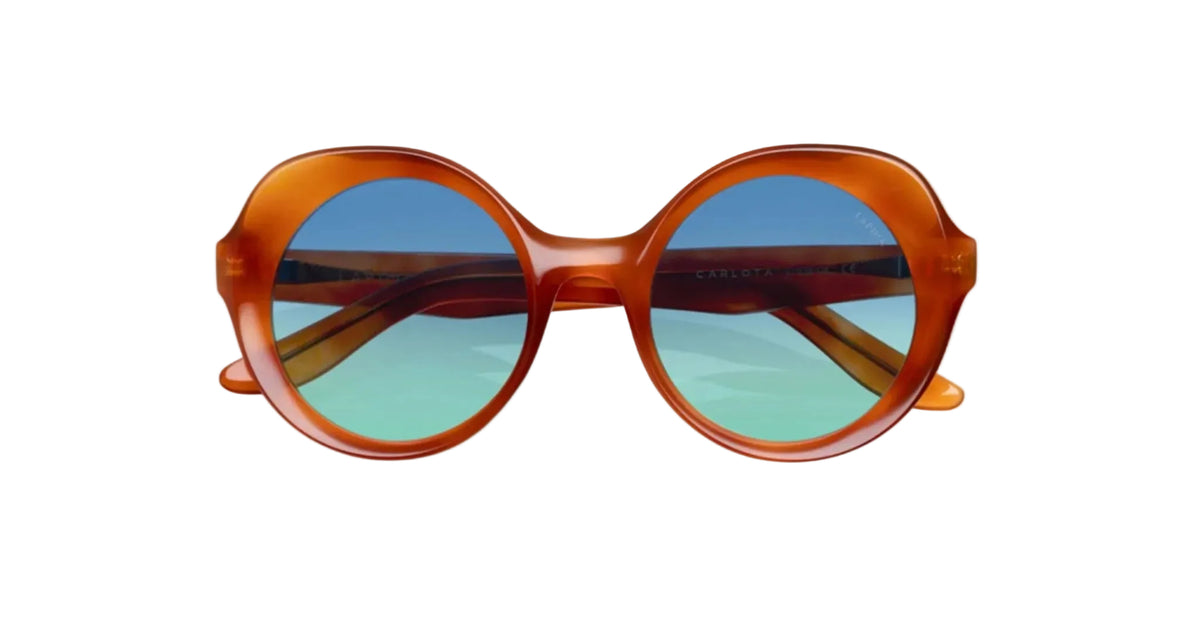 Front view of Lapima Carlota sunglasses in Caramel Blue Sky, featuring oversized round frames crafted from translucent caramel-orange acetate, a sculpted saddle bridge, bold curved rims, and blue gradient lenses fading into turquoise green.