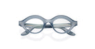 The COMING SOON Lapima Isa features translucent gray-blue oval eyeglasses with thick frames and slightly upturned edges, showcased on a white background.