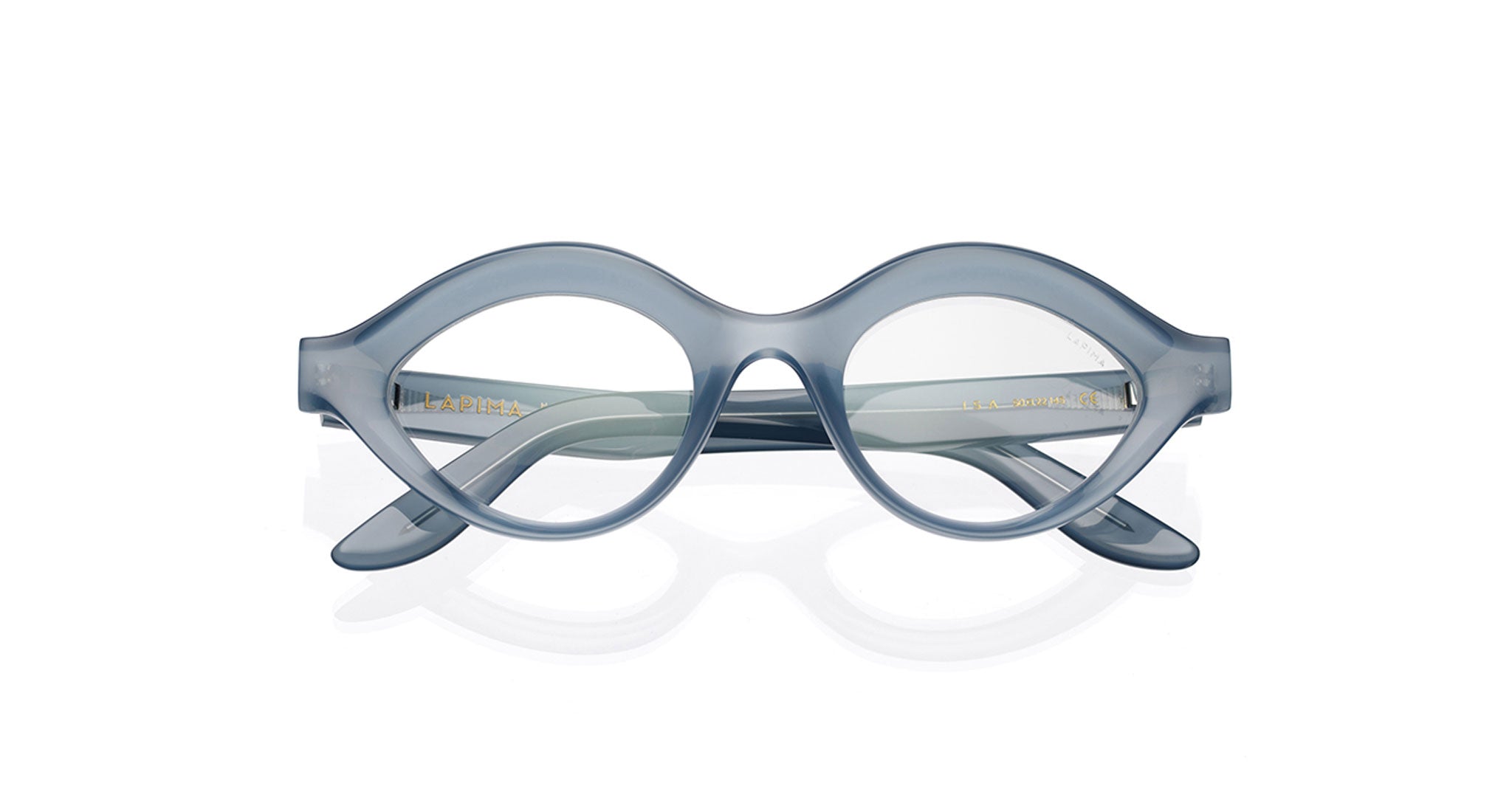 The COMING SOON Lapima Isa features translucent gray-blue oval eyeglasses with thick frames and slightly upturned edges, showcased on a white background.