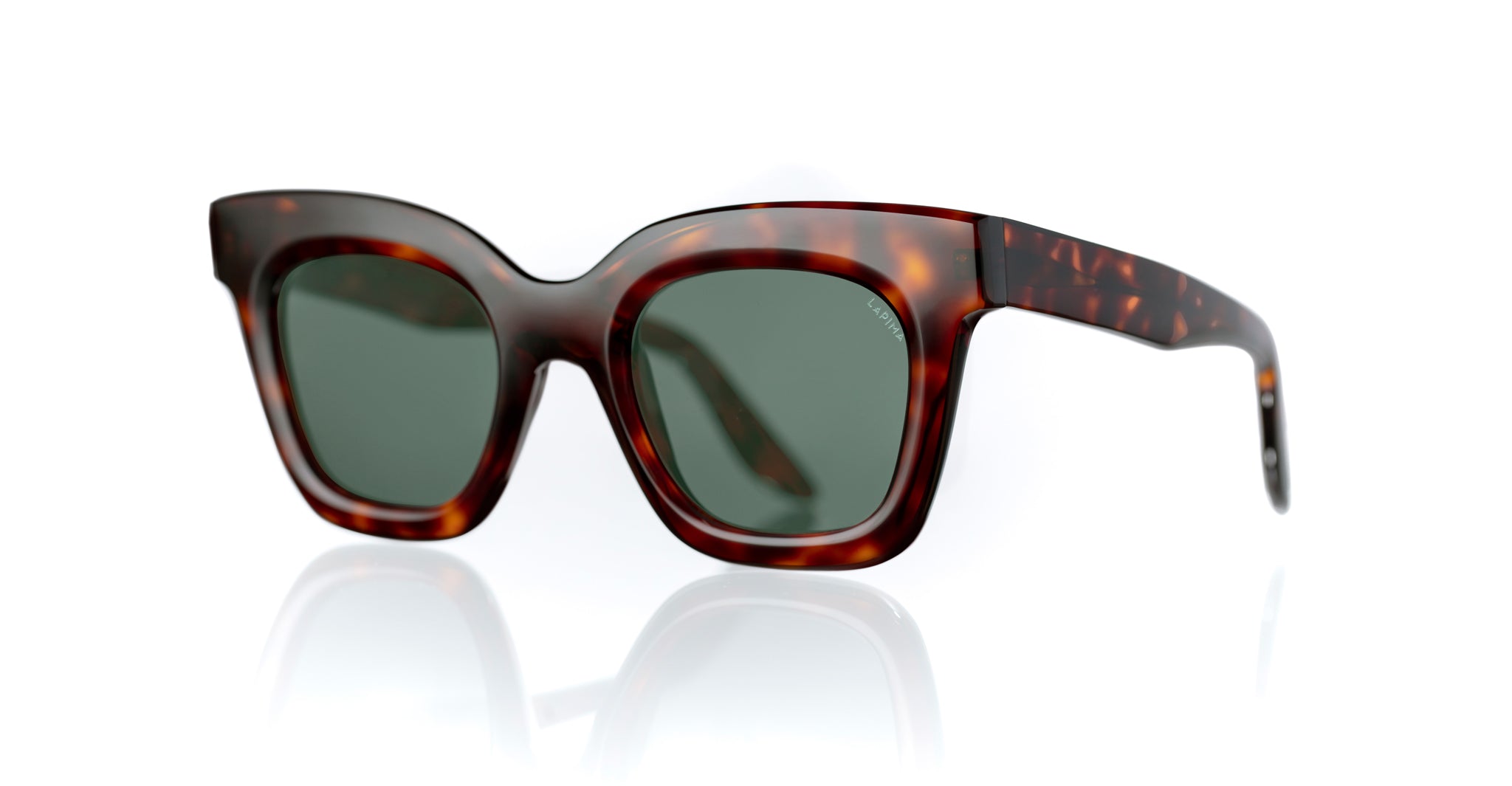 Lapima Lisa X sunglasses featuring thick, square tortoiseshell frames and dark green lenses are shown on a white reflective surface.