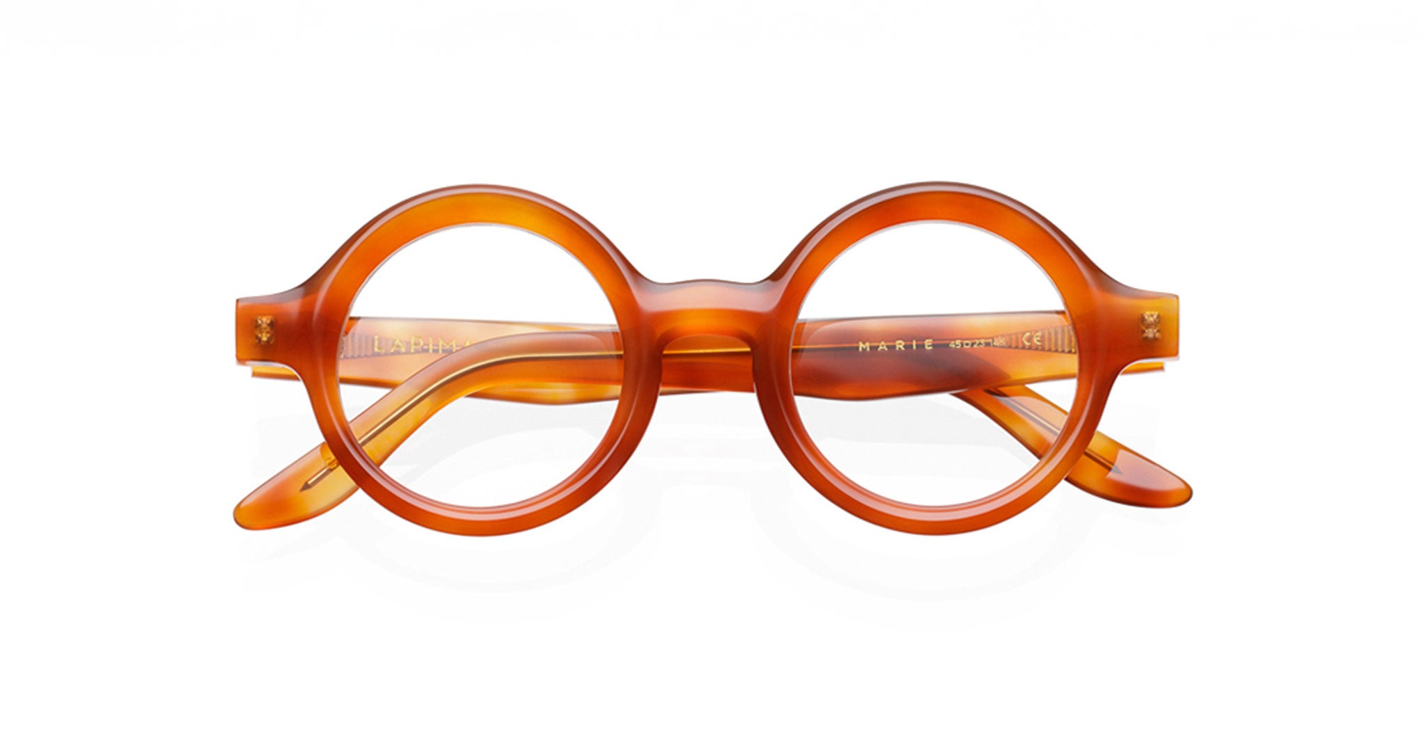 The Lapima Marie features round, thick frames made from Italian acetate in translucent amber. Vintage-inspired with oversized circular lenses and sturdy arms, these eyeglasses make a bold statement. Photographed on a white background.